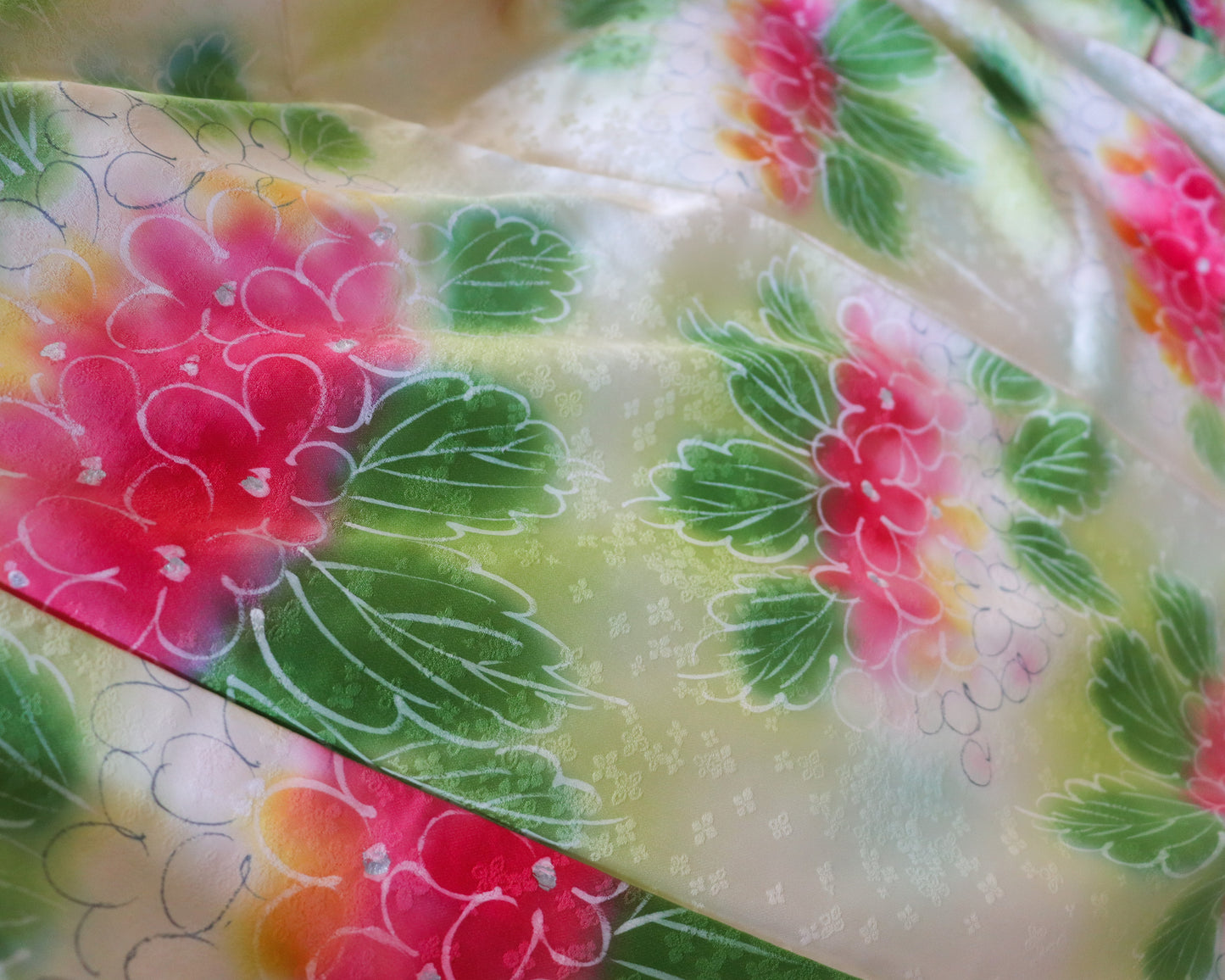 Vintage silk kimono in light pastel green with cute floral pattern. up close image of the fabric in natural light.