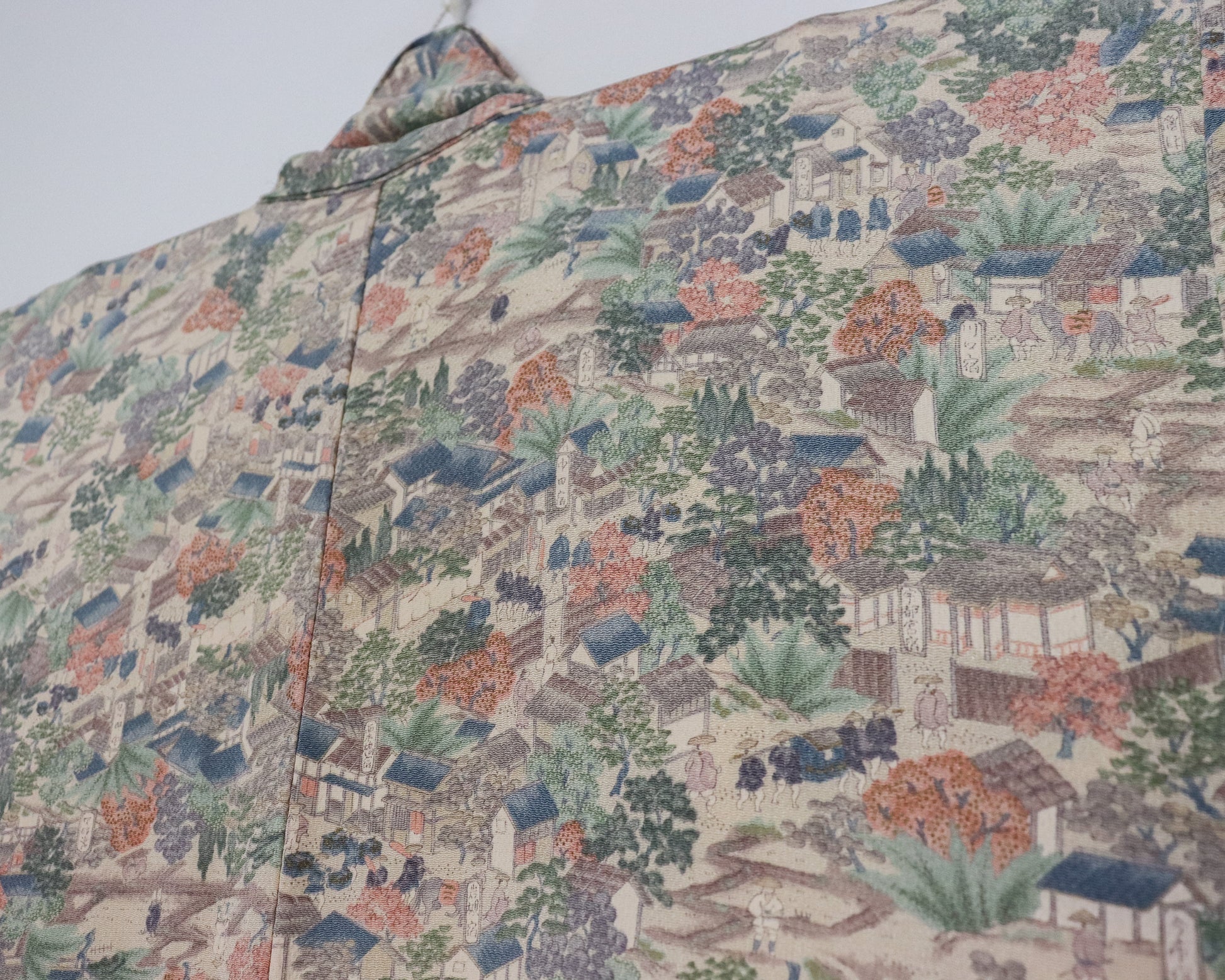 vintage silk kimono with unique pattern of people, buildings and nature.  close up image of the fabric.