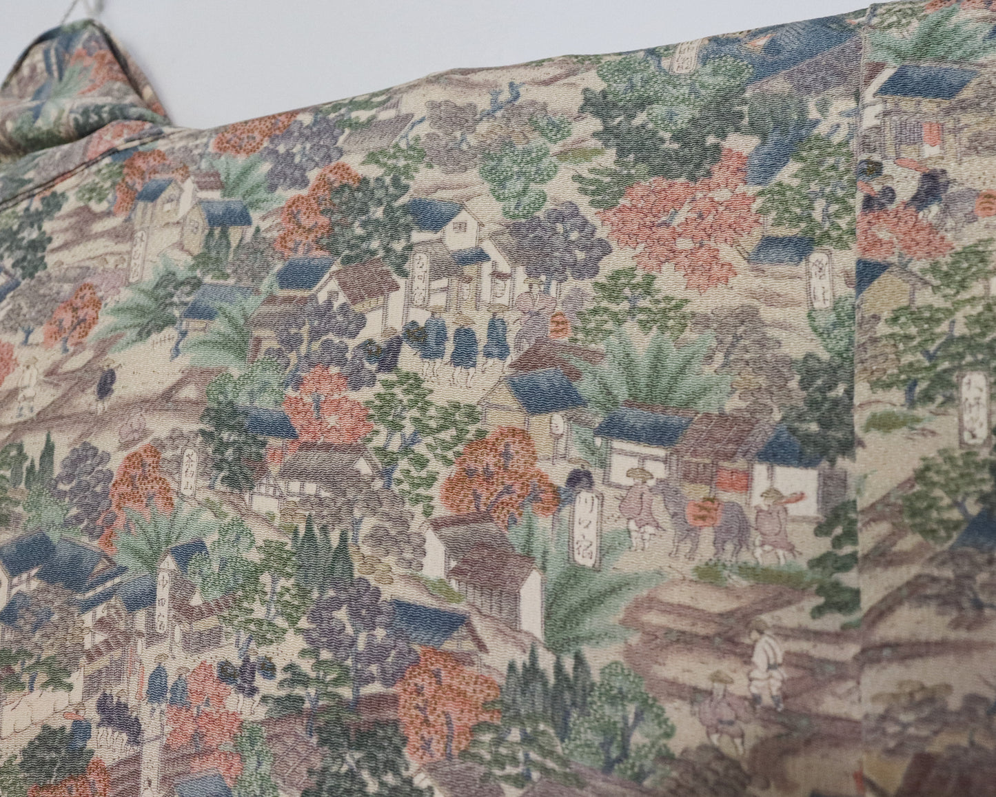 vintage silk kimono with unique pattern of people, buildings and nature.  close up image of the silk kimono fabric.