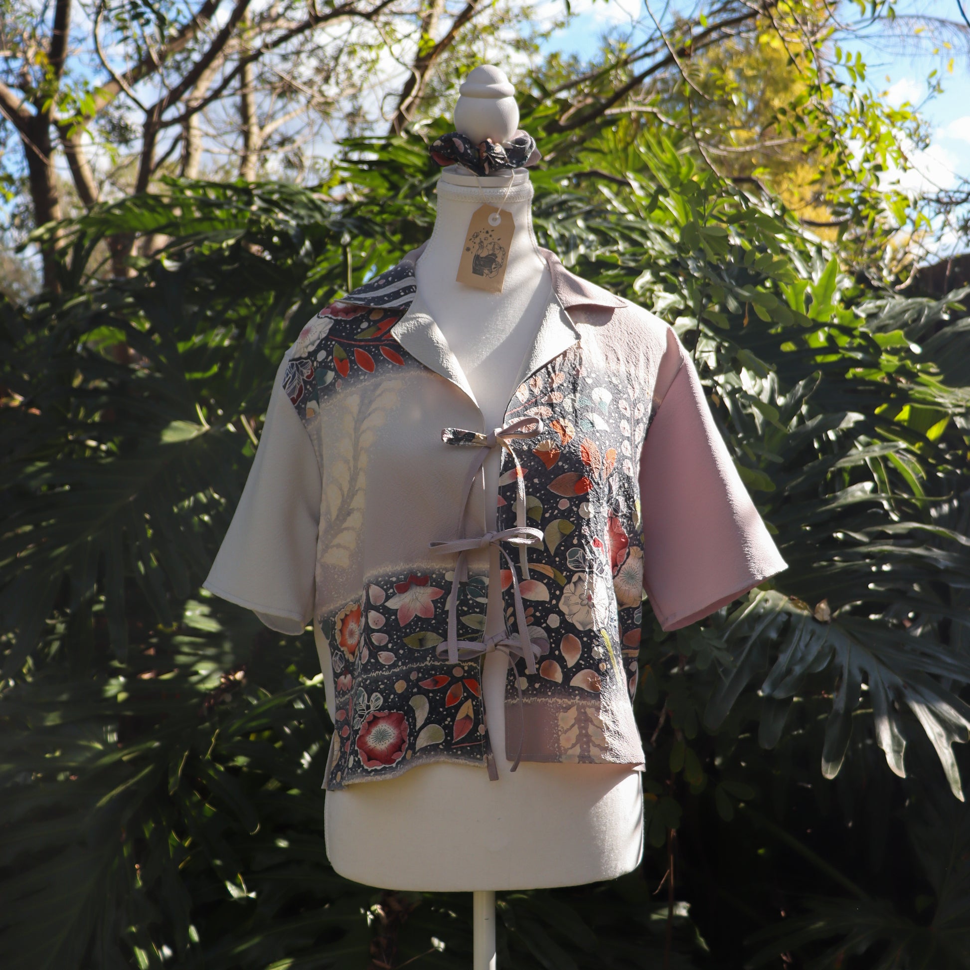 Mannequin wearing a floral-patterned shirt against a natural background