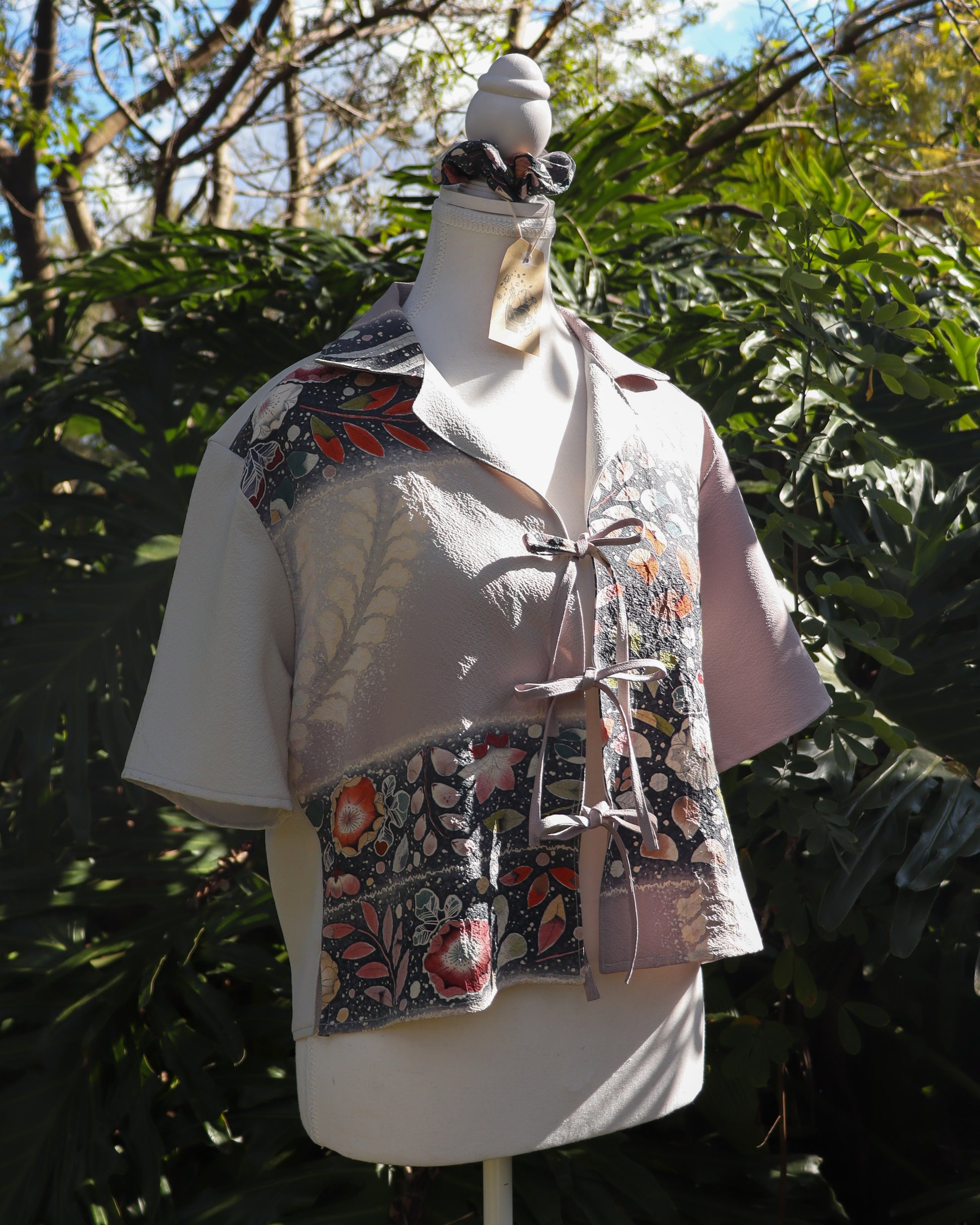 Mannequin wearing a silk shirt with floral pattern against a natural background