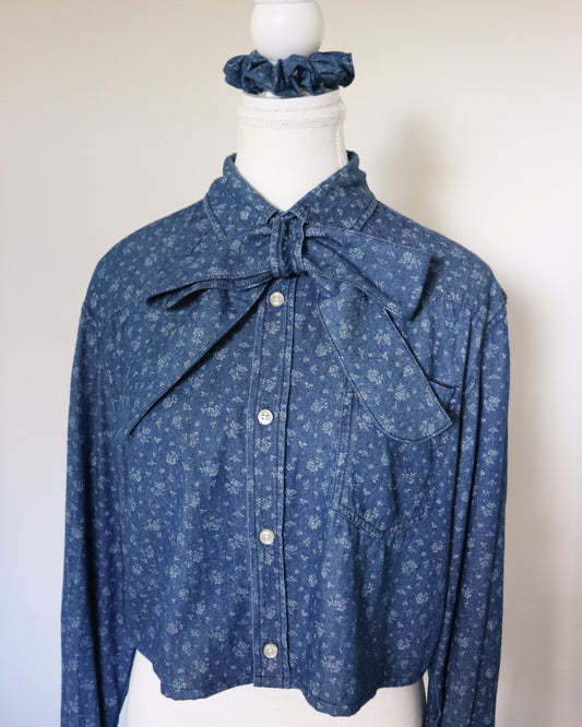 Blue floral blouse with a bow on a mannequin against a white background