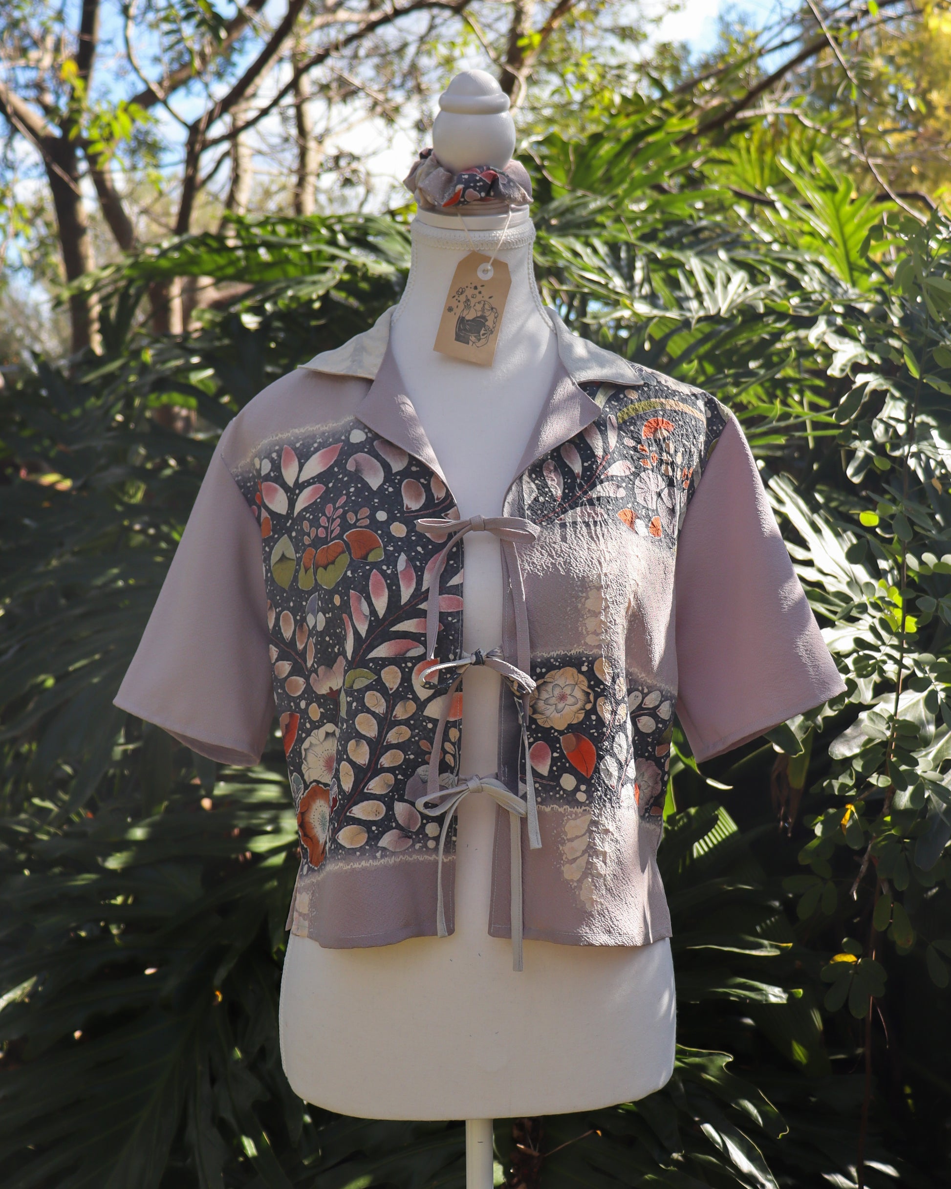 Mannequin wearing a floral-patterned shirt against a green leafy background
