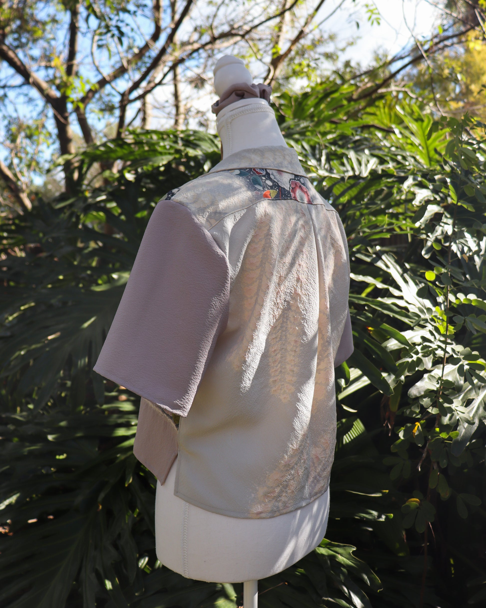 Mannequin wearing a silk shirt with floral pattern against a natural background