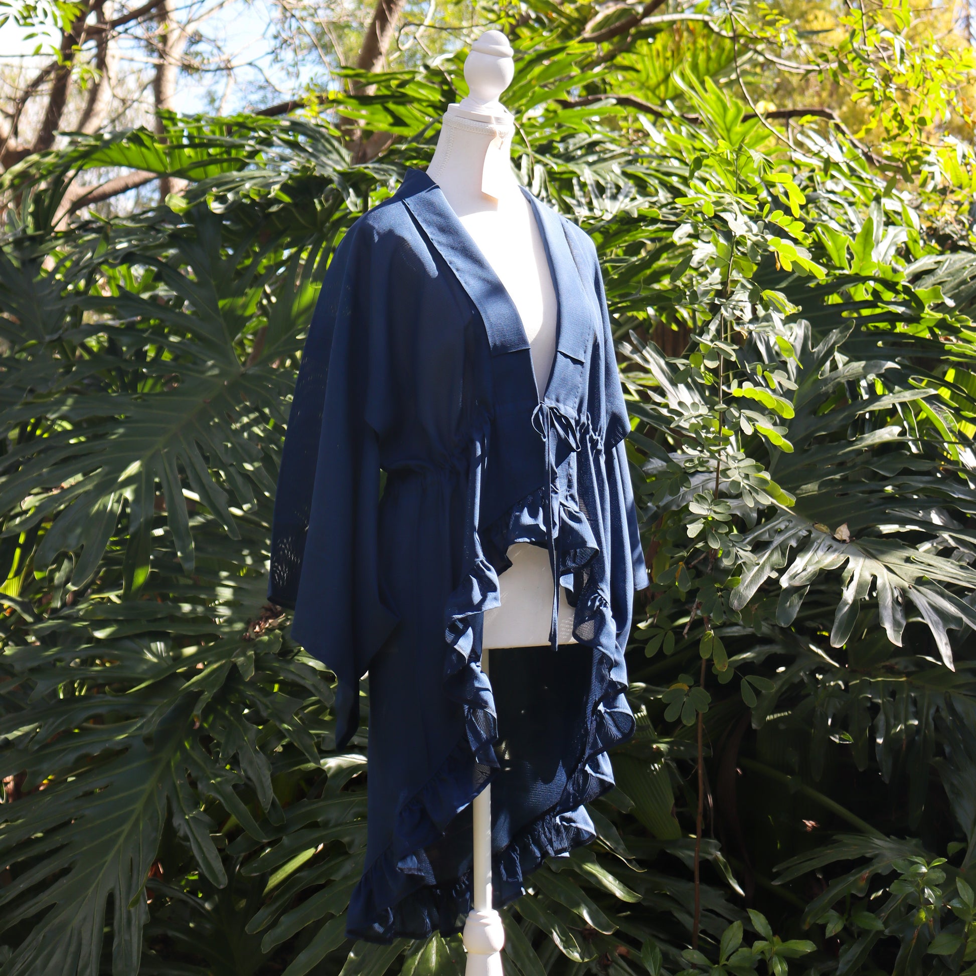 Navy blue kimono cardigan on a mannequin against a green leafy background