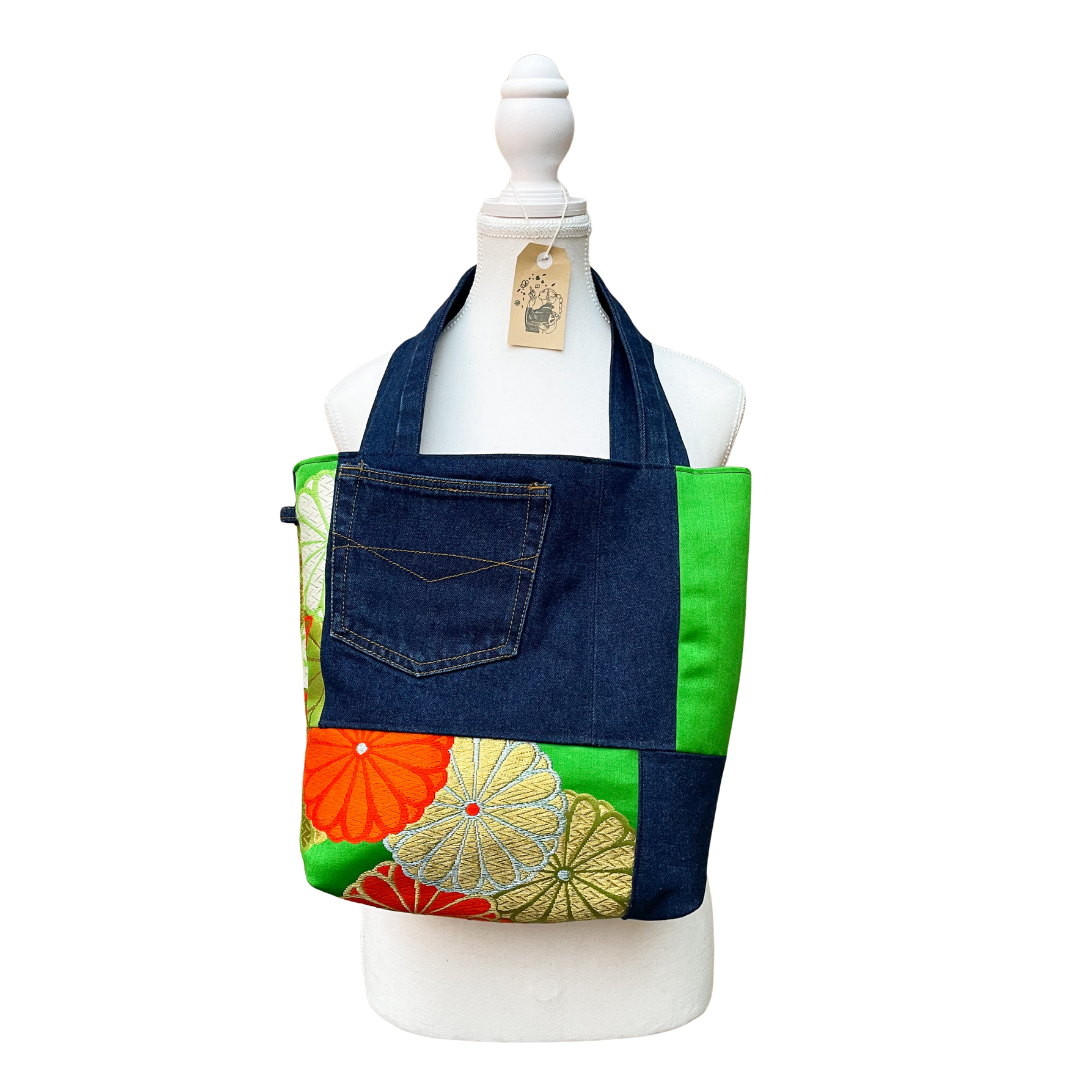 Colorful denim tote bag with floral patterns on a mannequin against a white background