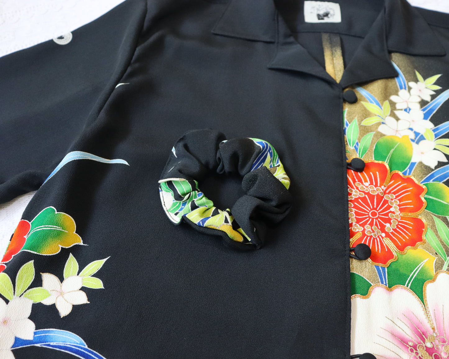 Black scrunchie with colorful pattern on a black garment with floral designs