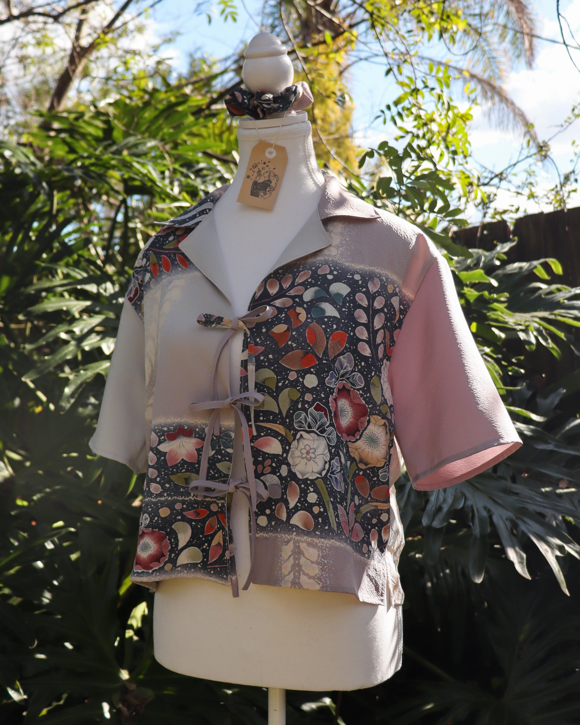 Mannequin wearing a floral patterned shirt with pink sleeves against a natural background