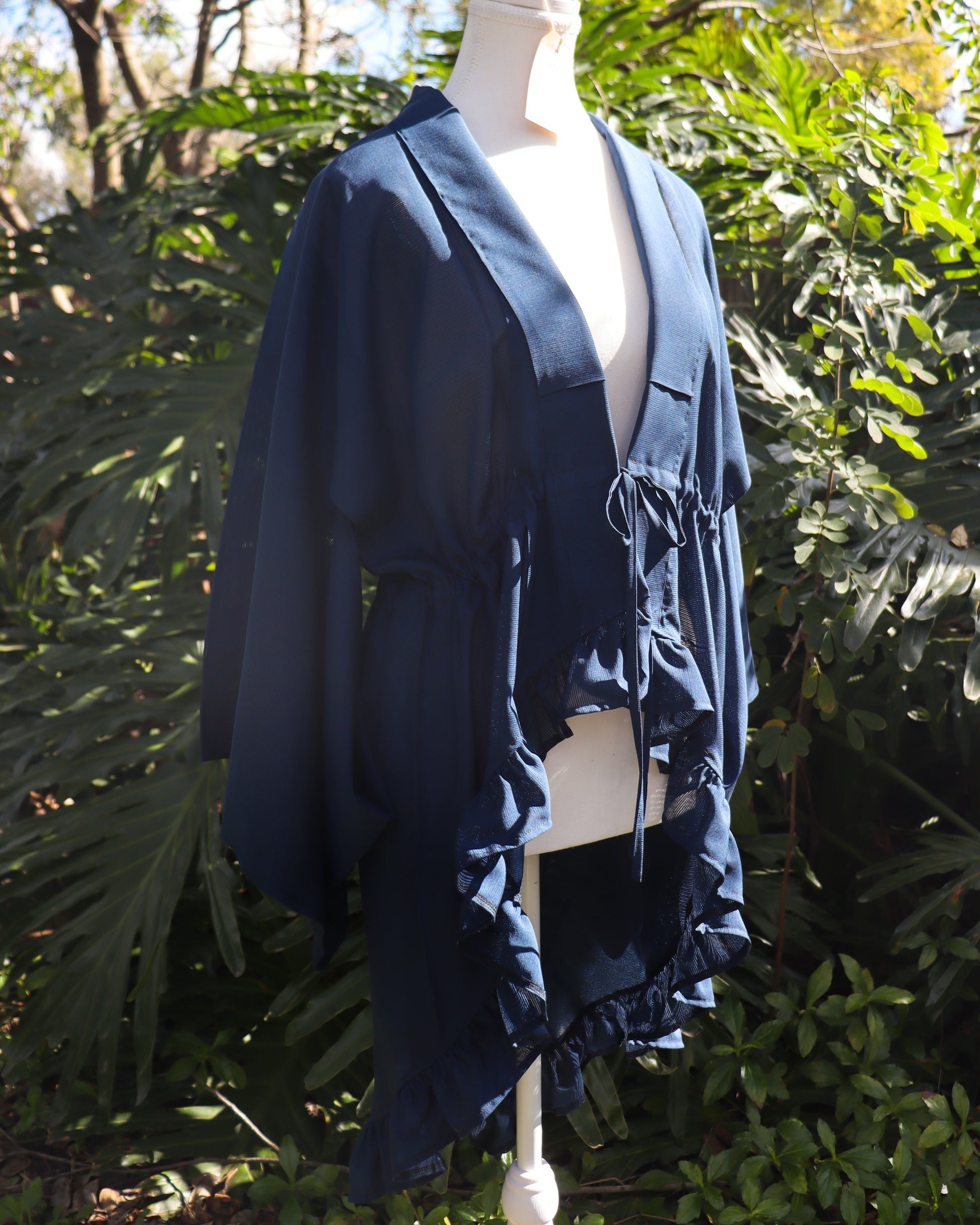 Navy blue kimono cardigan on a mannequin against a green leafy background