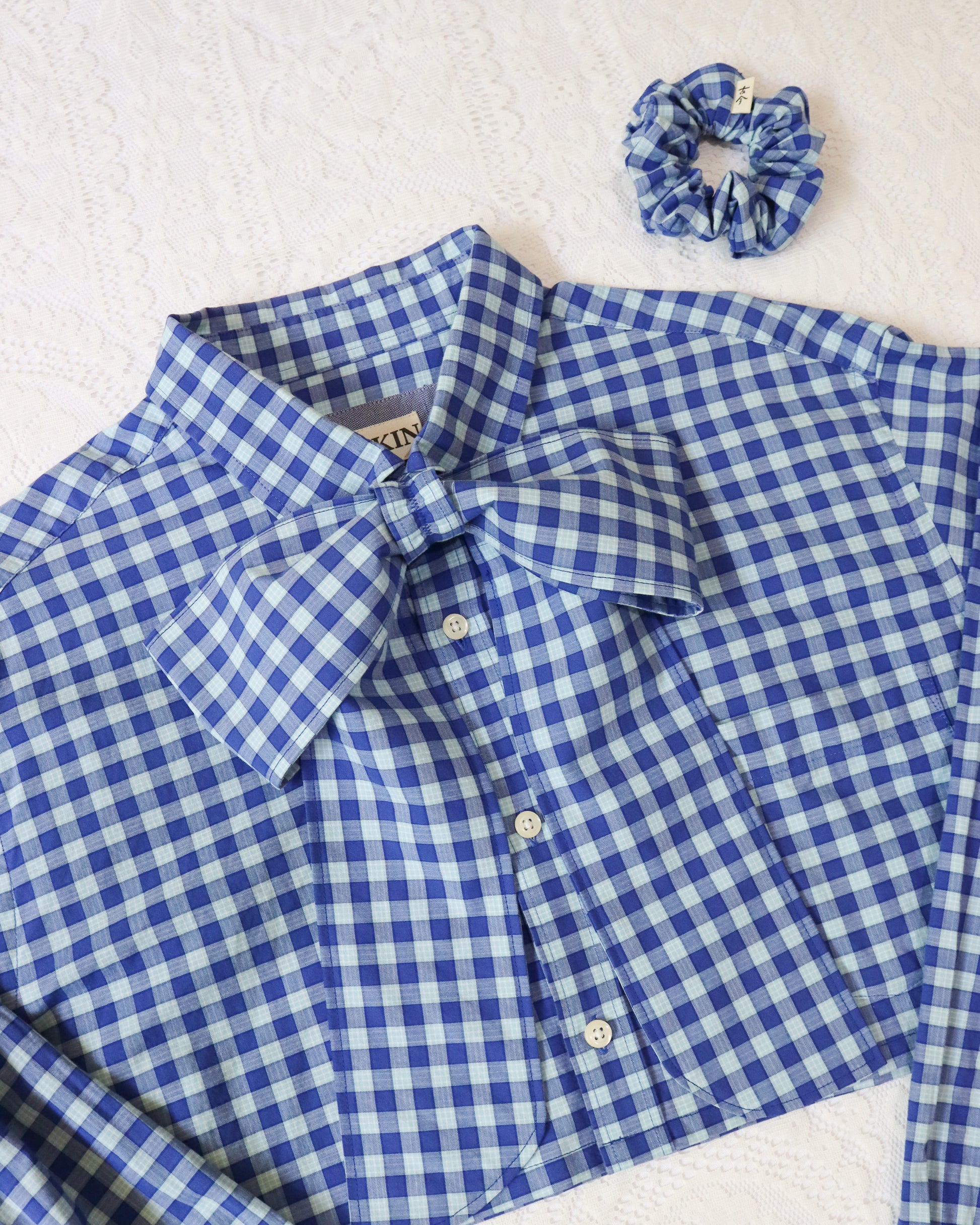 Blue and white checkered shirt with a matching scrunchie on a light background