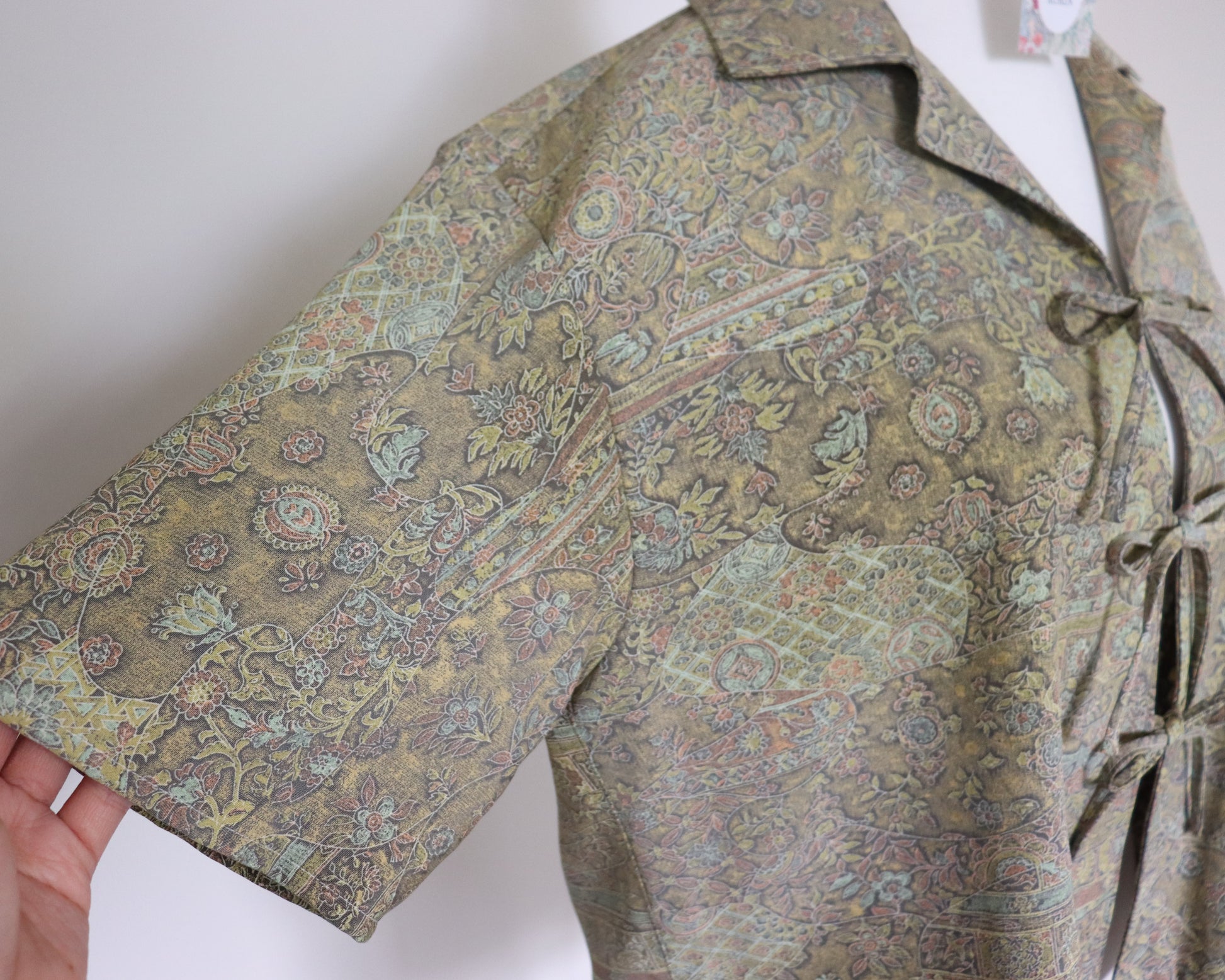 Patterned shirt held by a hand on a white background
