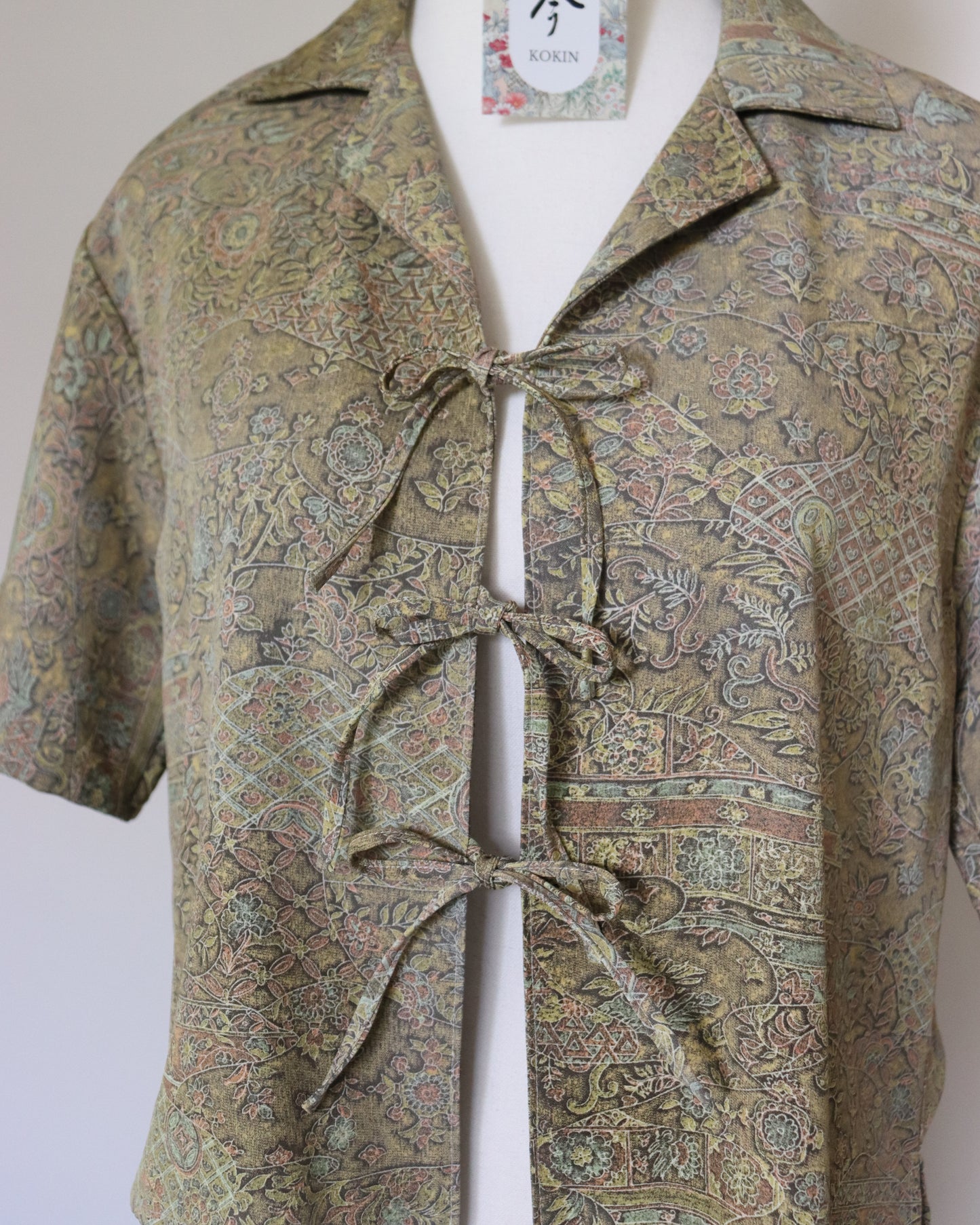 Patterned shirt with a tie on a mannequin against a plain background