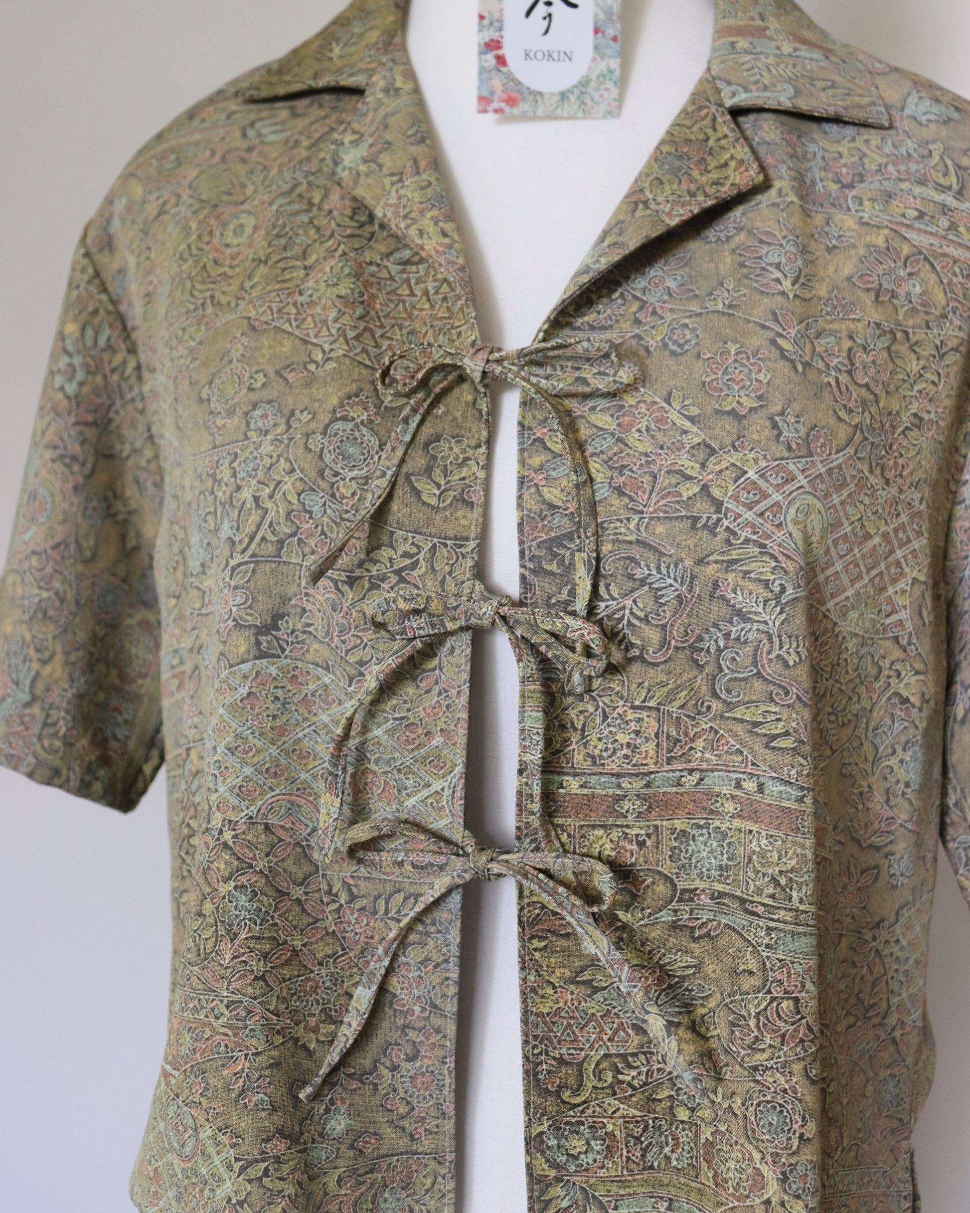Patterned shirt with a tie on a mannequin against a plain background