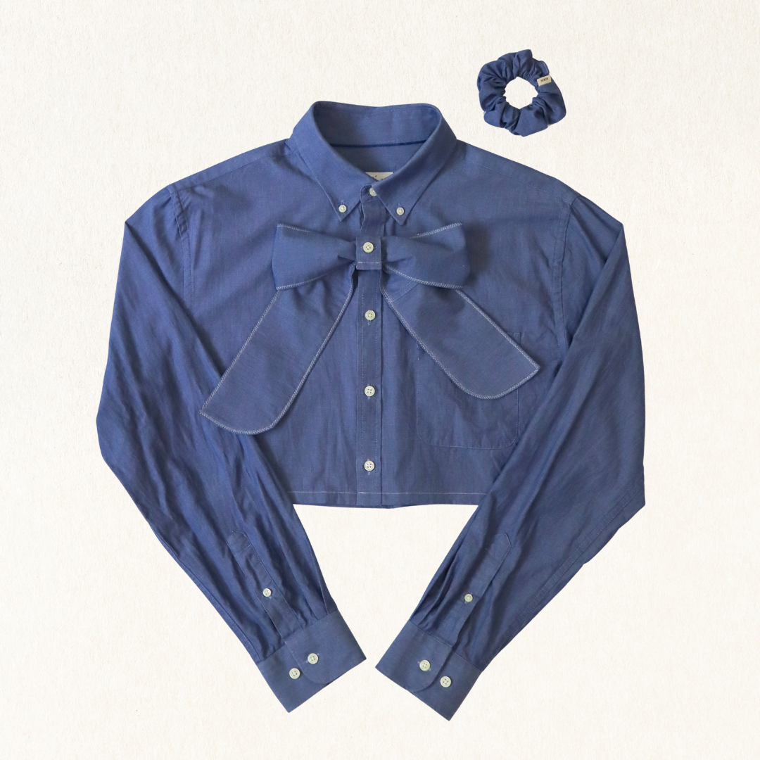 Blue shirt with bow detail and matching scrunchie on a white background
