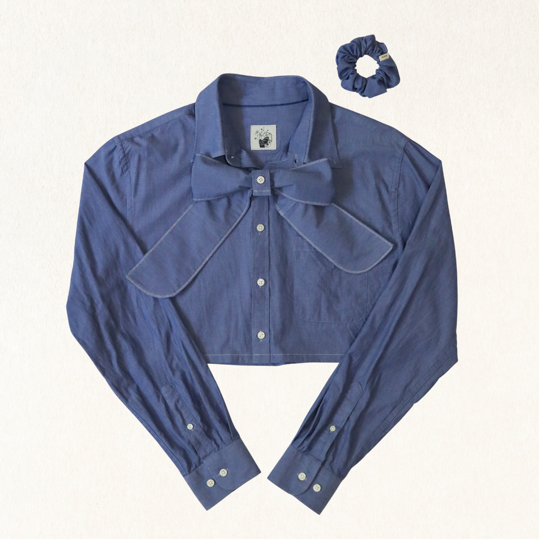 Blue shirt with bow detail and matching scrunchie on a white background