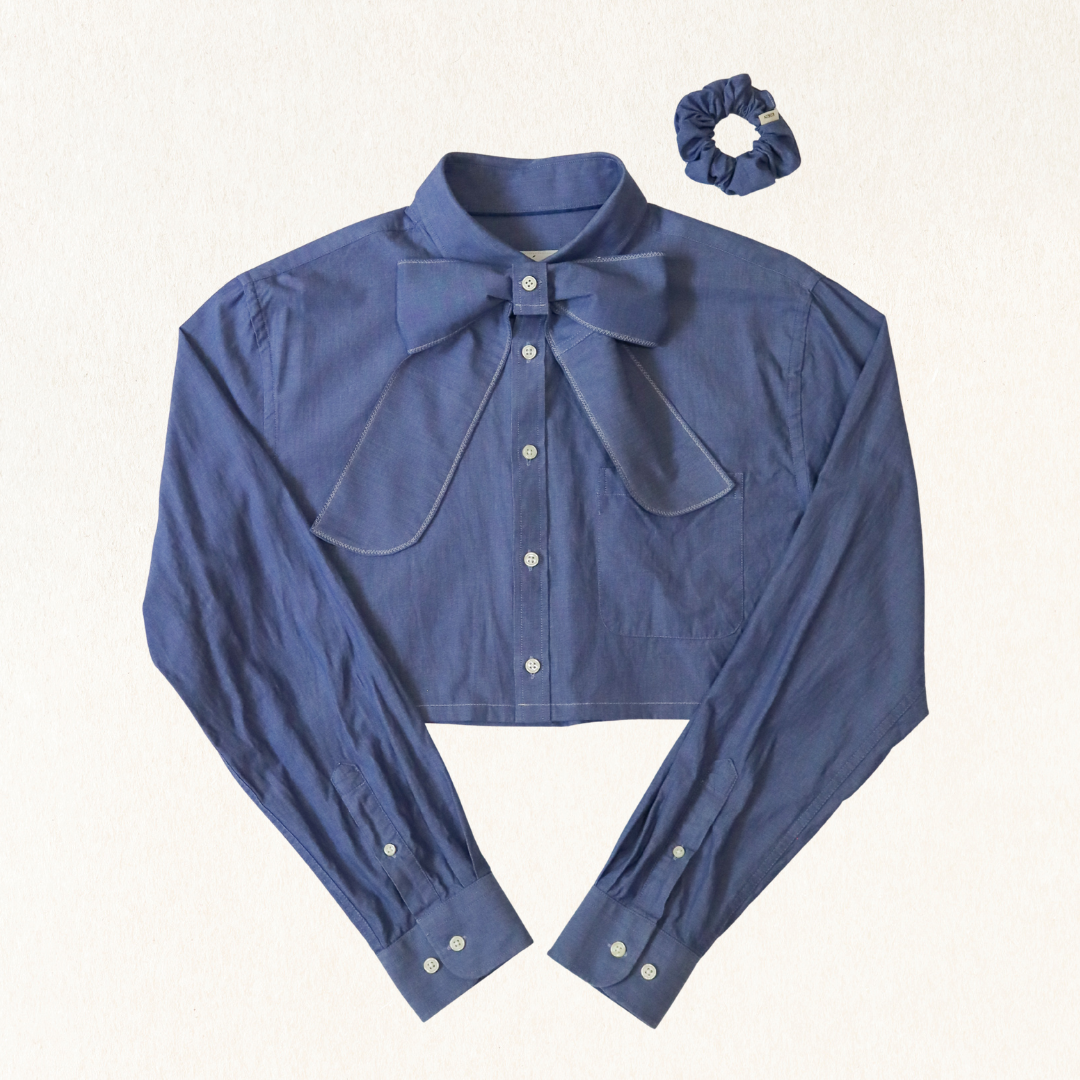 Blue shirt with bow detail and matching scrunchie on a white background