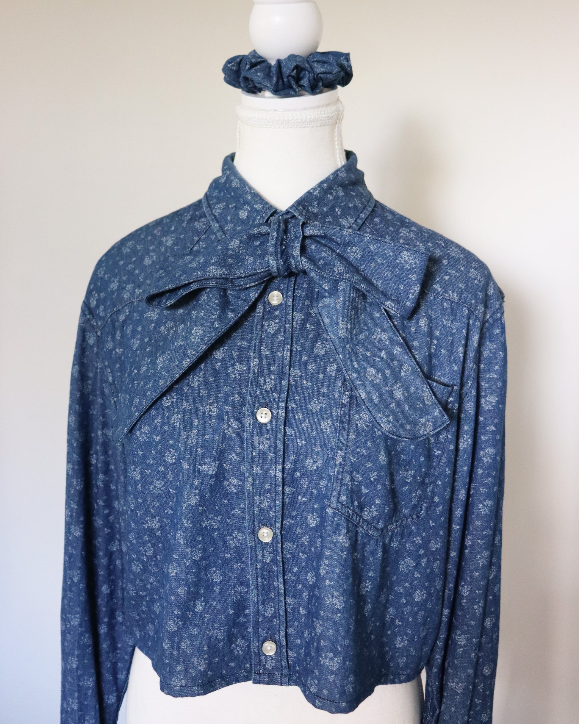 Blue floral blouse with a bow on a mannequin against a white background