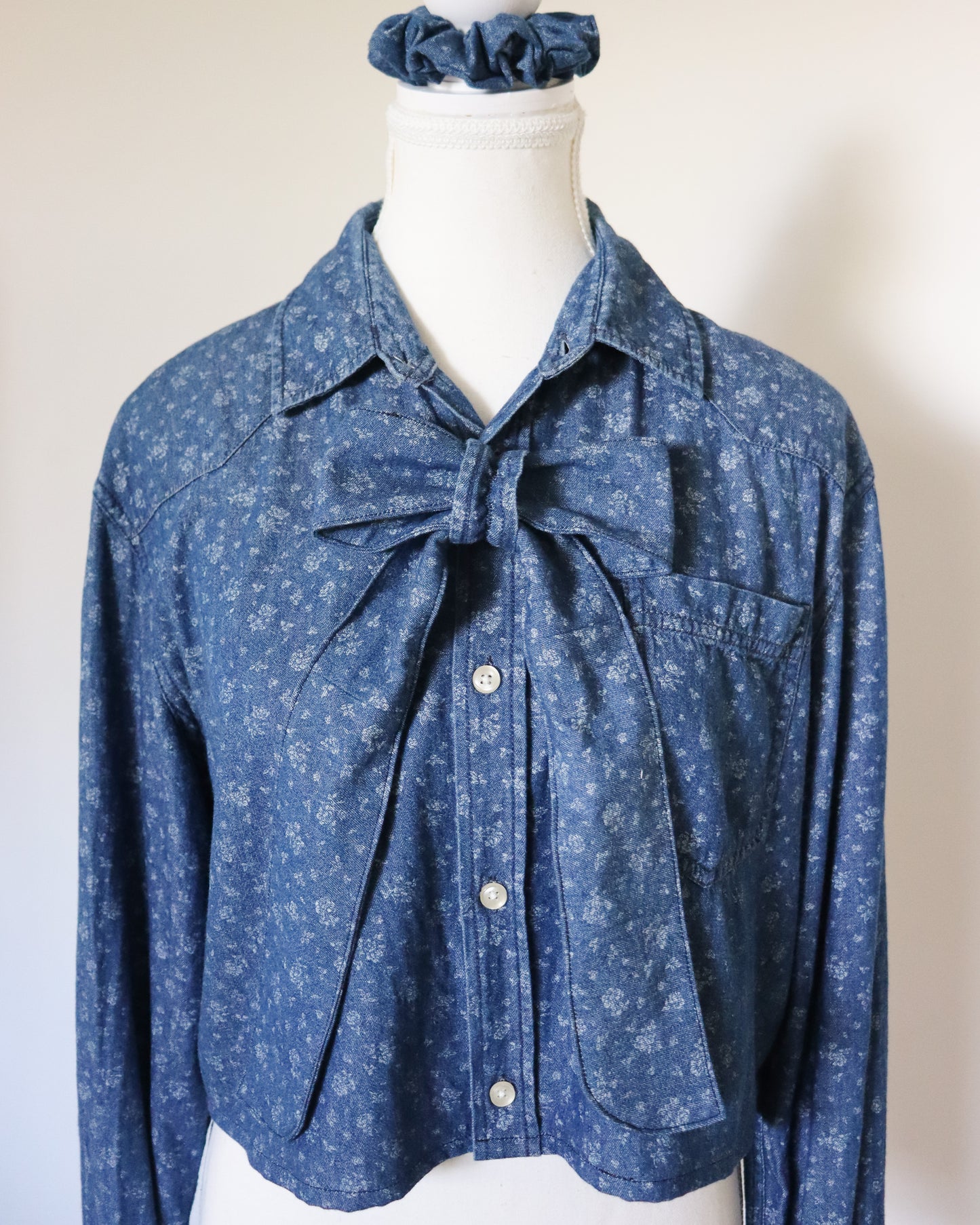 Blue floral blouse with a bow on a mannequin against a white background