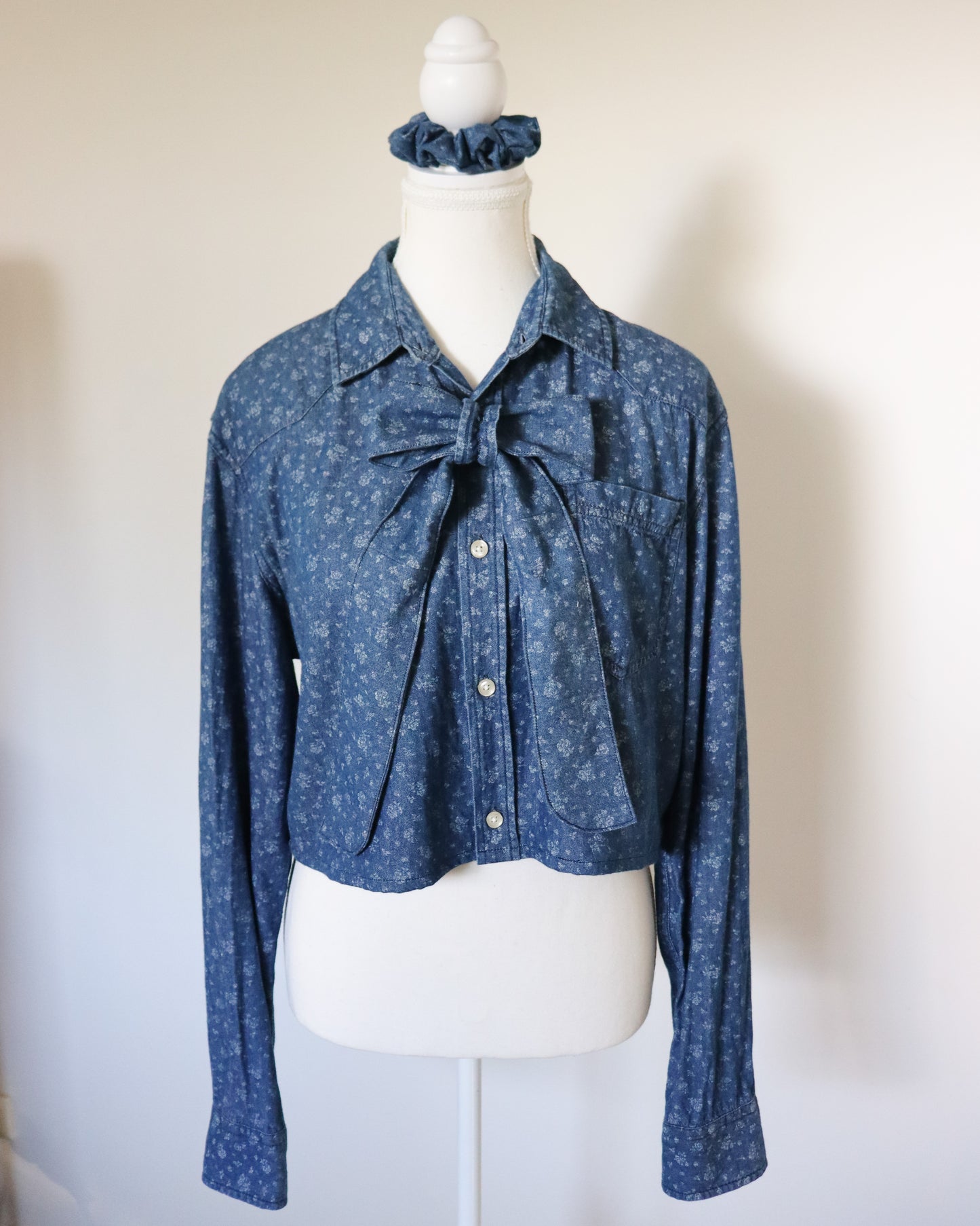 Blue patterned blouse with a tie detail on a mannequin against a white background