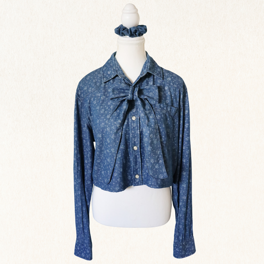 Blue patterned blouse with a tie detail on a mannequin against a white background