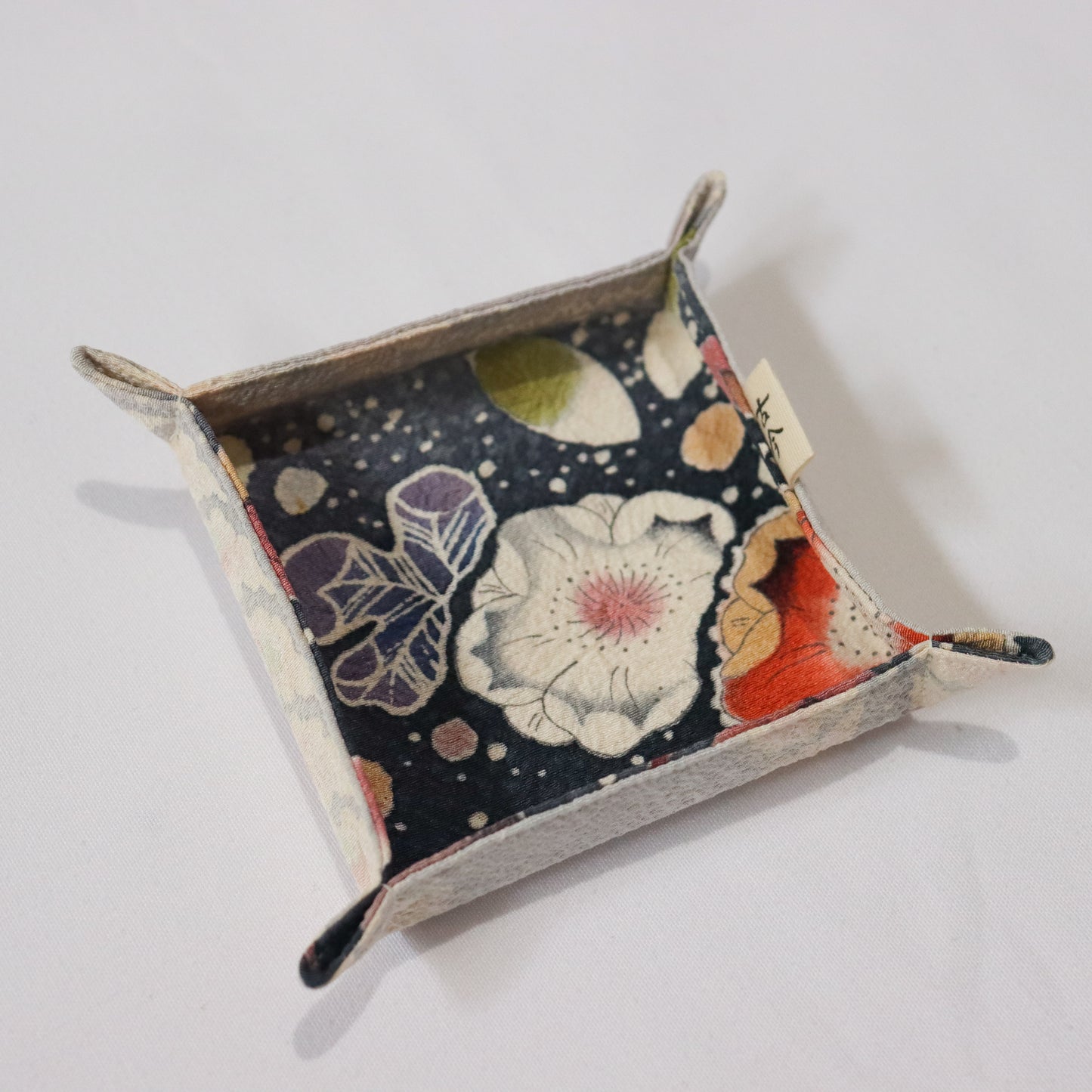 Fabric tray in colourful fabric with nature motif pattern in a white background.