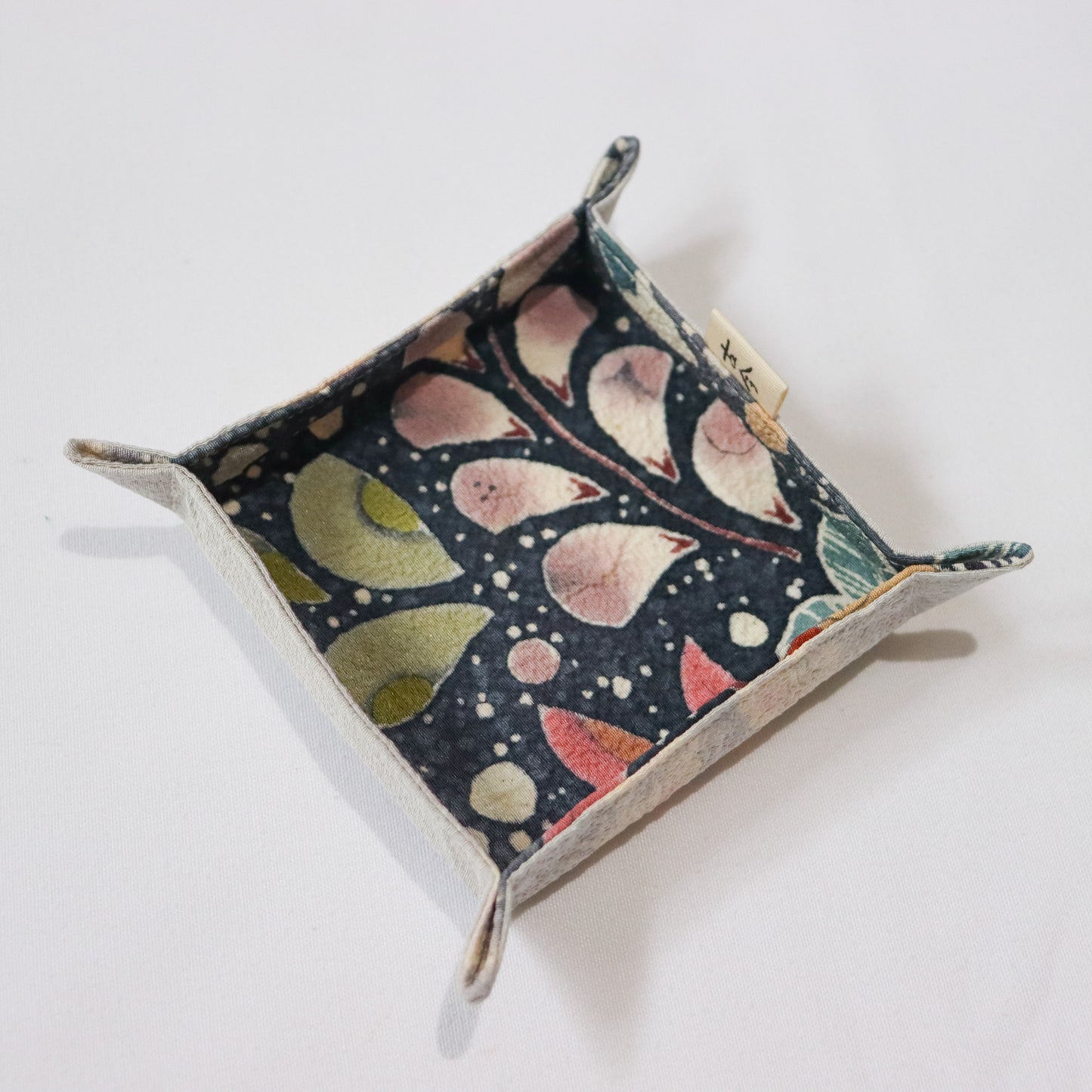 Fabric tray in colourful fabric with nature motif pattern in a white background.