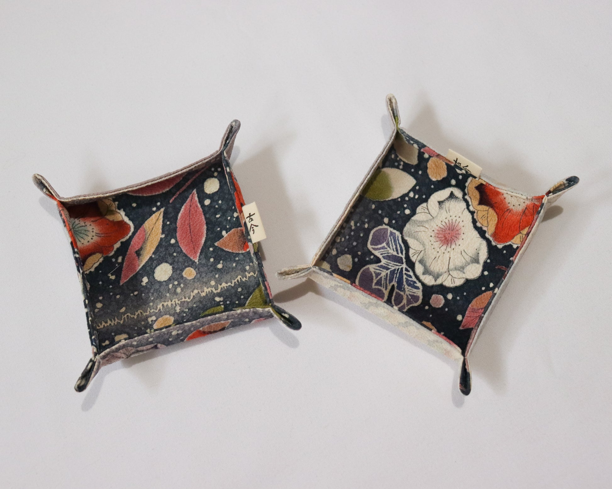 Fabric trays in colourful fabric with nature motif pattern in a white background.