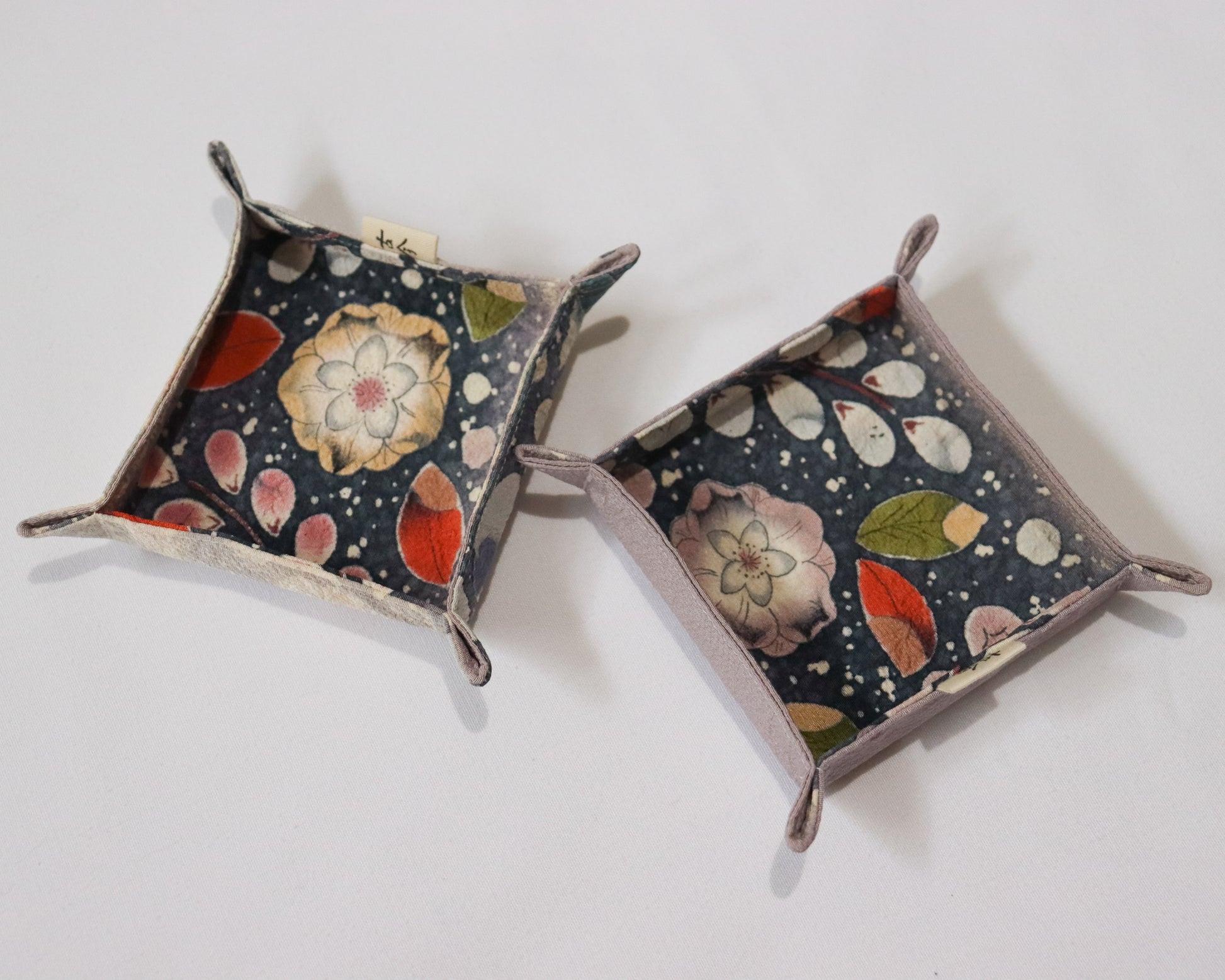 Fabric trays in colourful fabric with nature motif pattern in a white background.