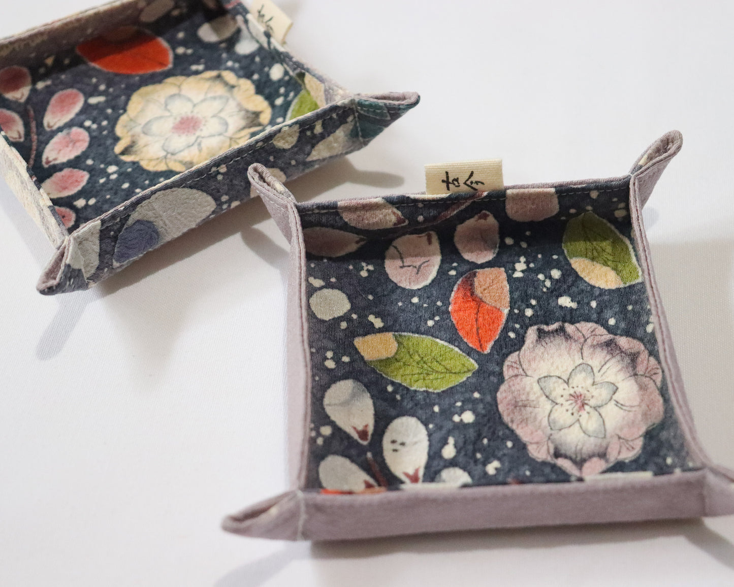 Fabric trays in colourful fabric with nature motif pattern in a white background.