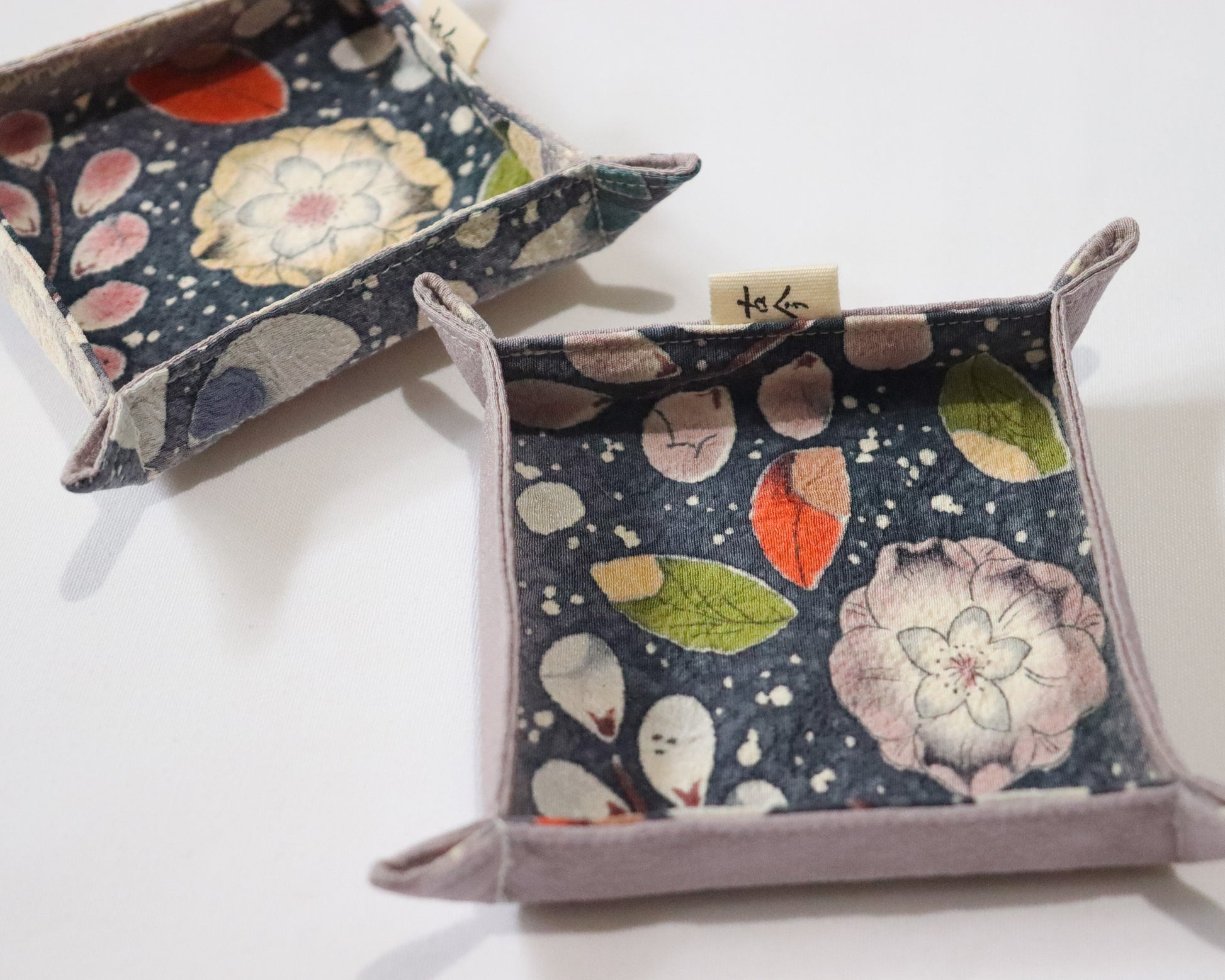 Fabric trays in colourful fabric with nature motif pattern in a white background.