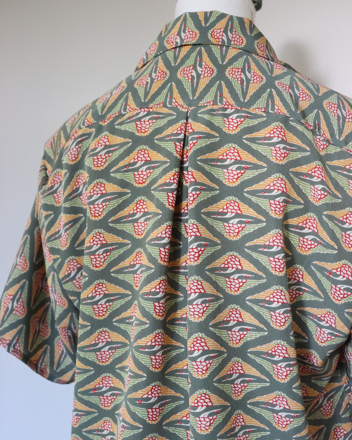 Mannequin wearing a colorful geometric patterned shirt against a plain background