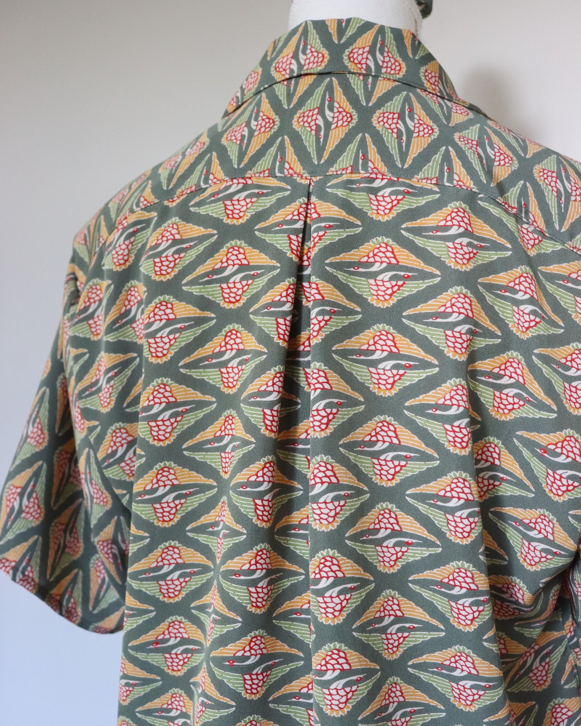 Mannequin wearing a colorful geometric patterned shirt against a plain background