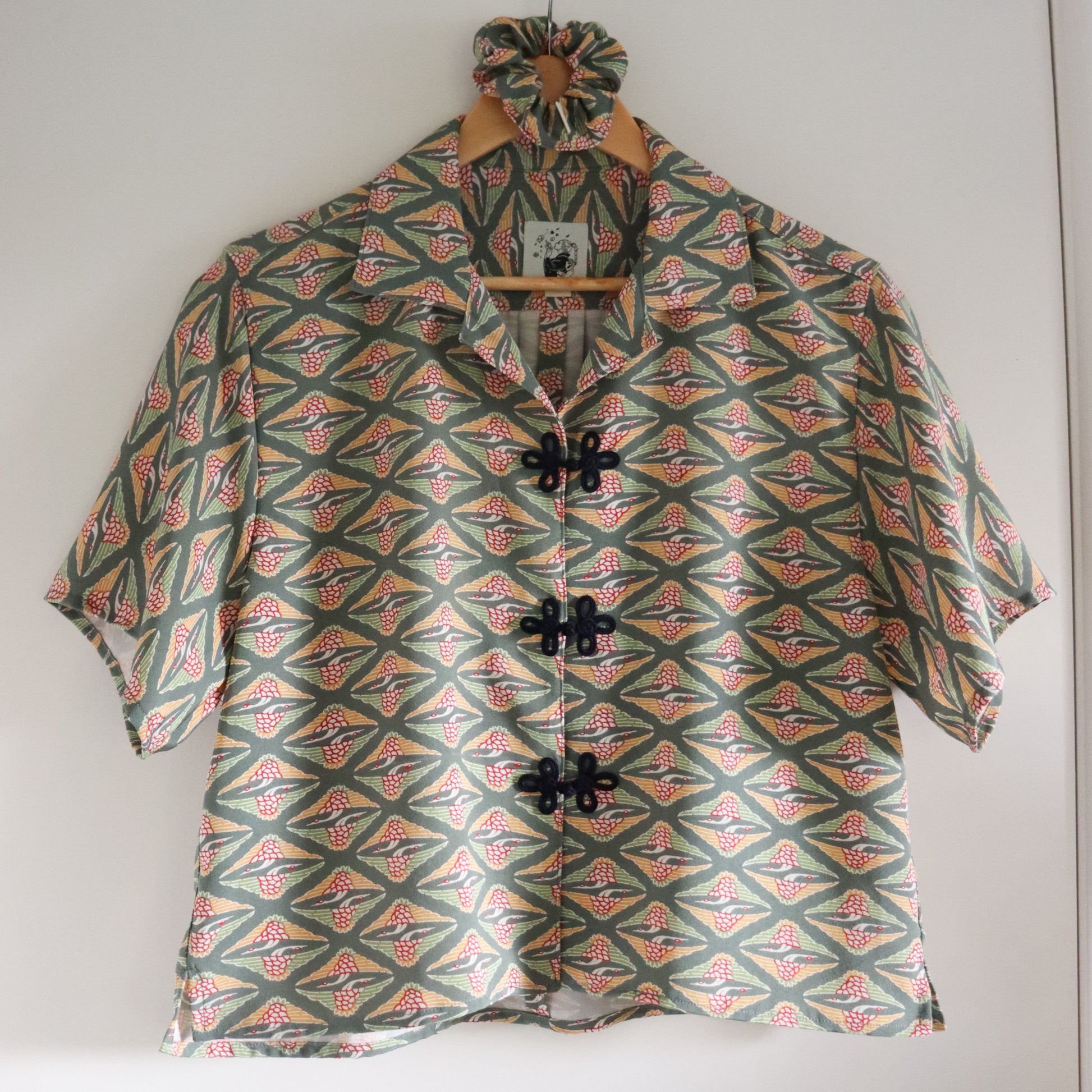 Short-sleeve shirt with geometric pattern on a hanger against a white wall