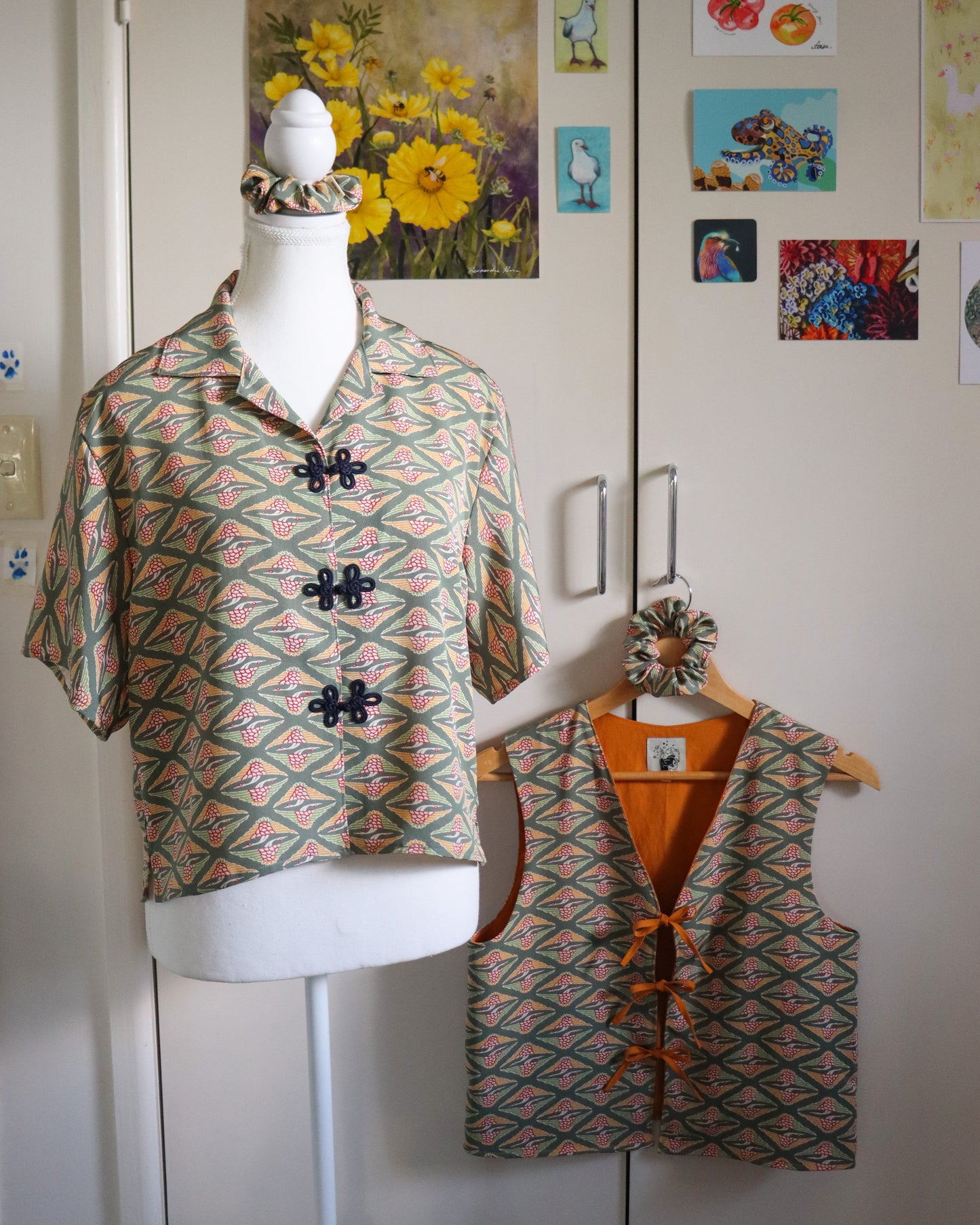 Mannequin wearing a patterned shirt with matching vest against a white wall with decorative elements.