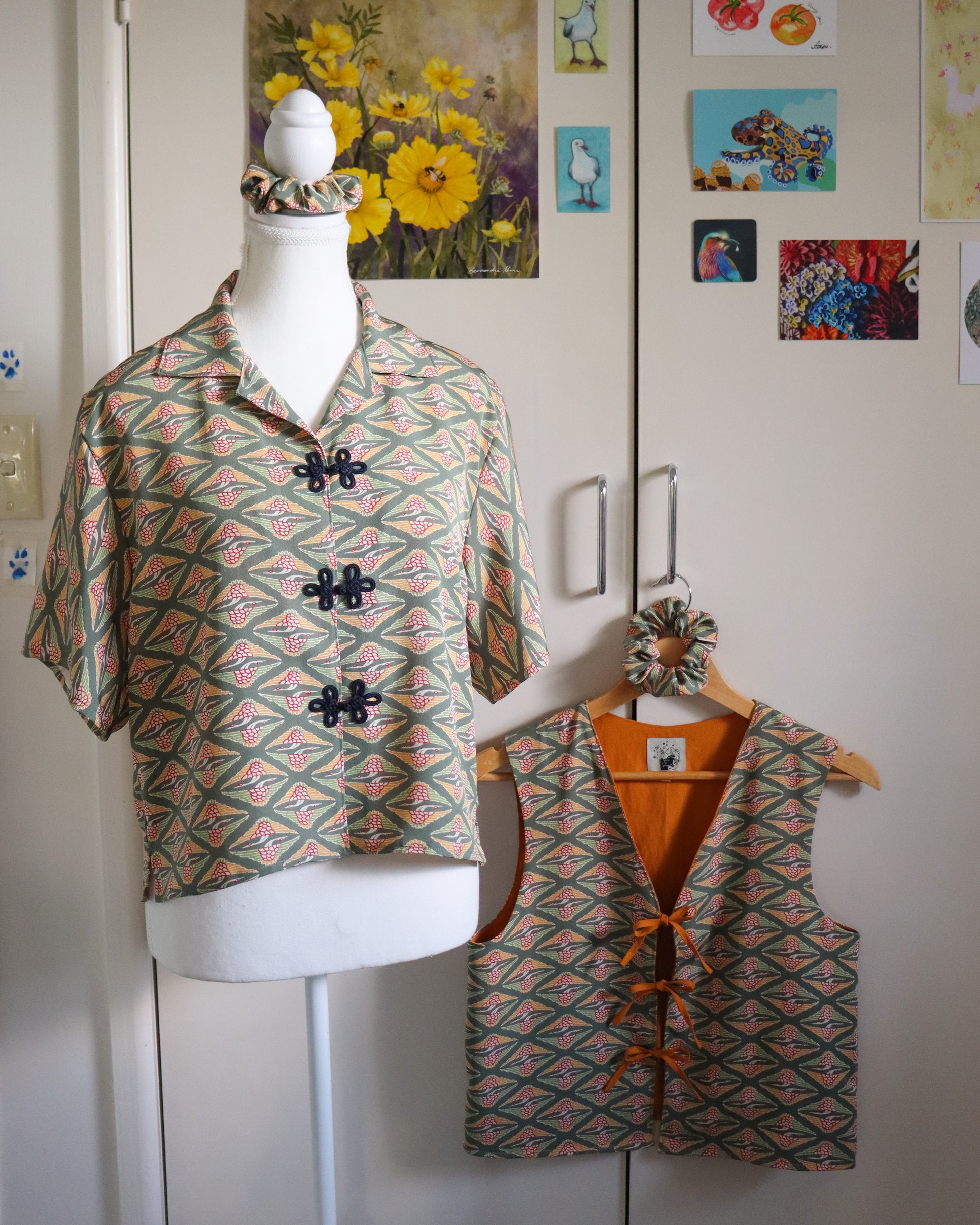 Mannequin wearing a patterned shirt with matching vest against a white wall with decorative elements.