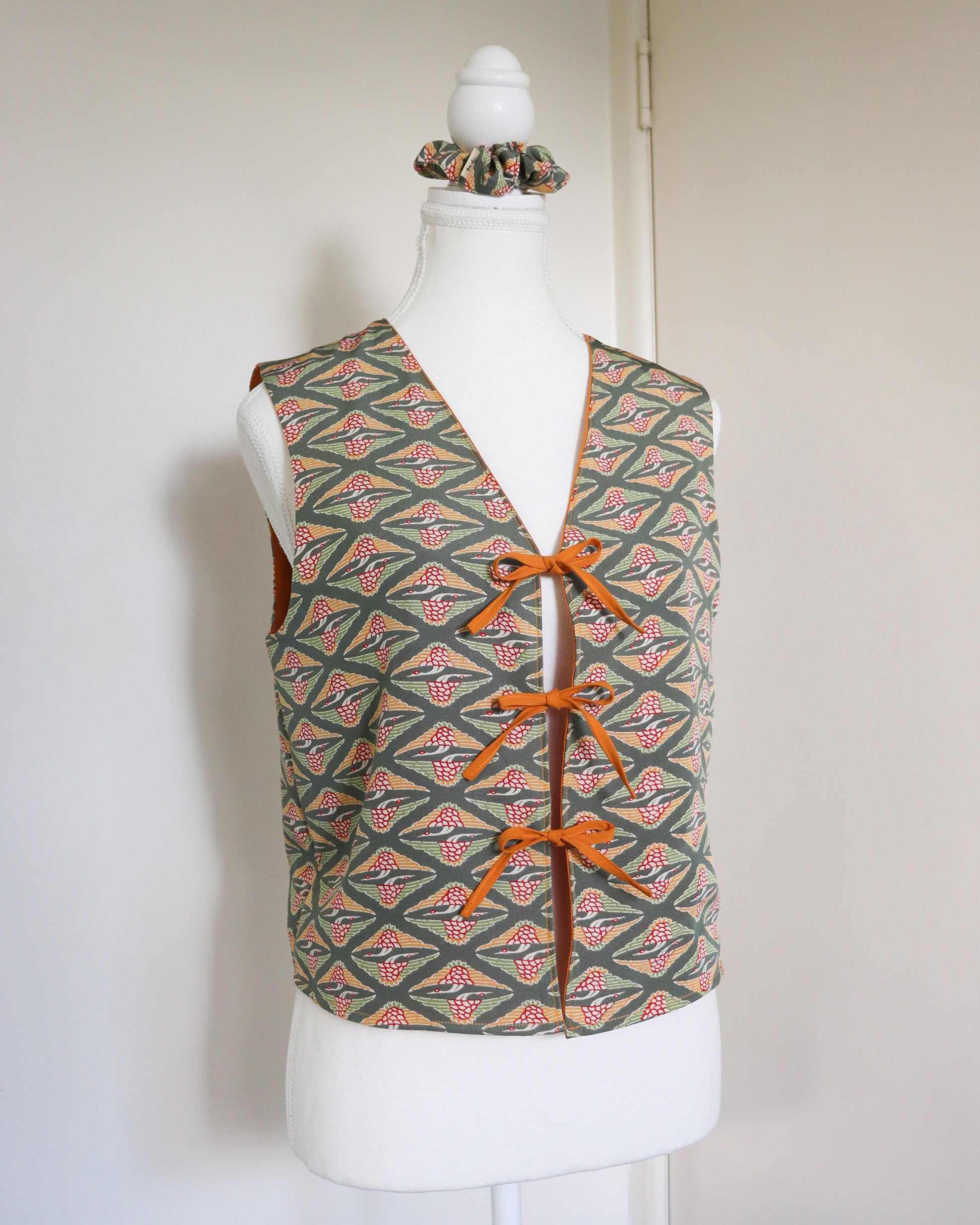 Patterned vest with orange laces on a mannequin against a plain background
