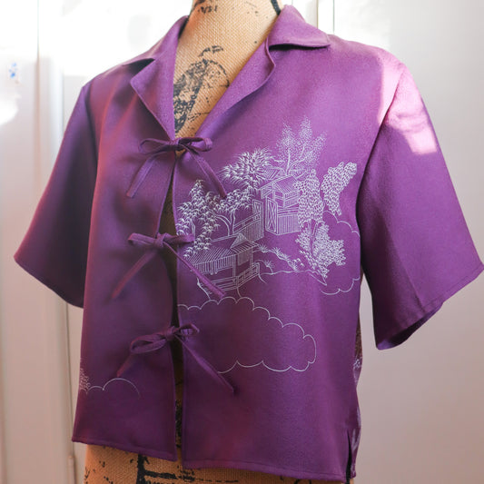 Purple blouse with white floral design on a mannequin against a plain background