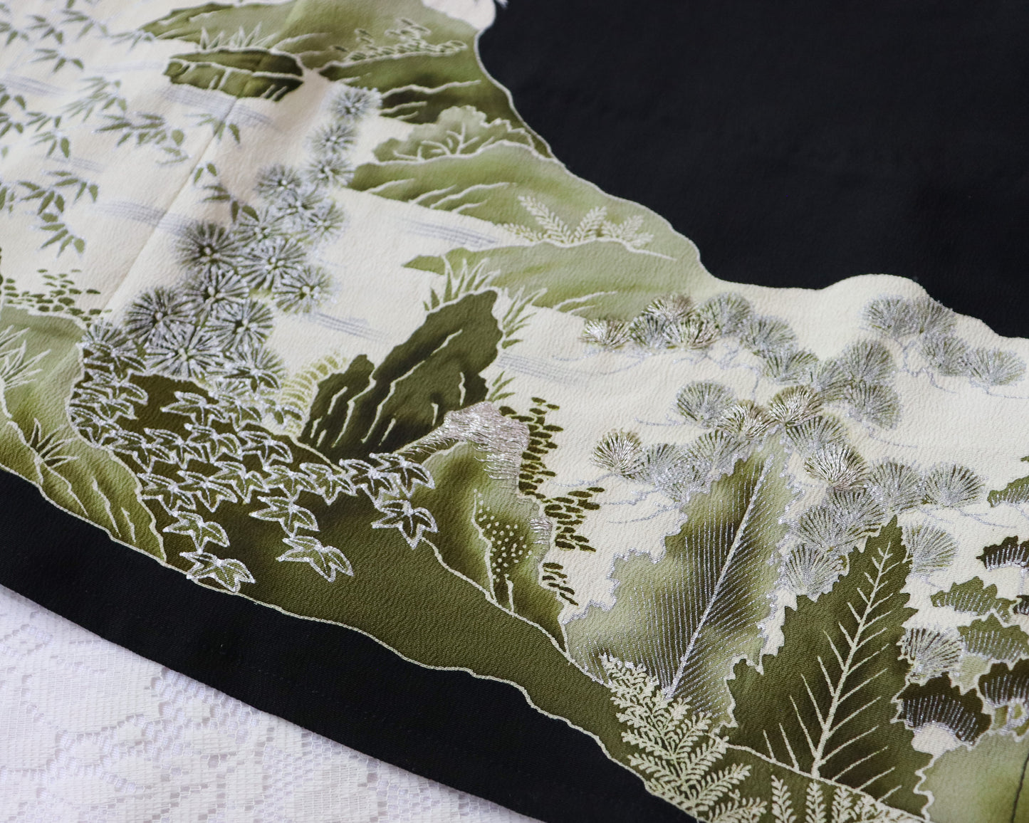 Close-up of a decorative fabric with green and white floral patterns on a black background.