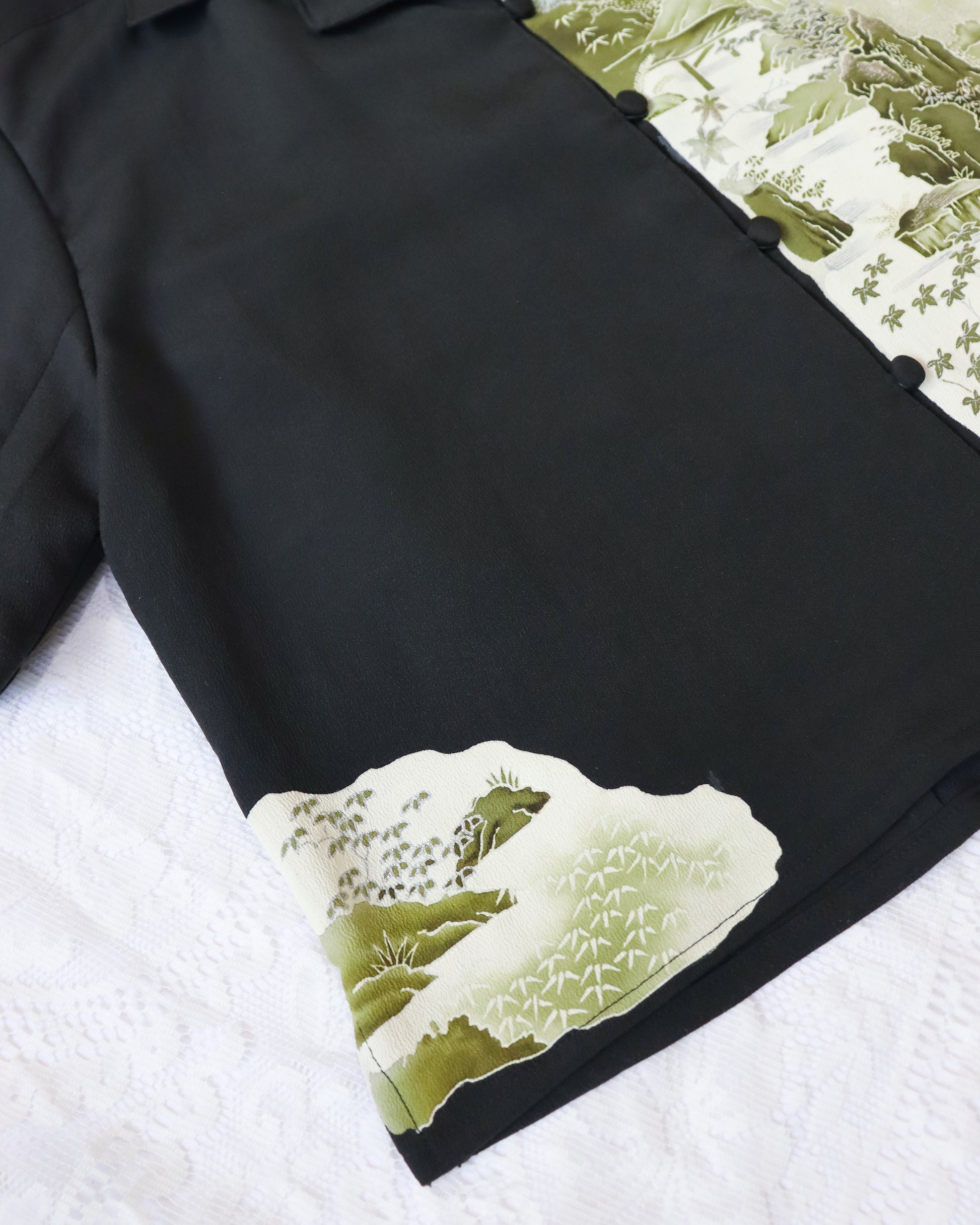 Black shirt with green floral pattern on sleeve against a white background