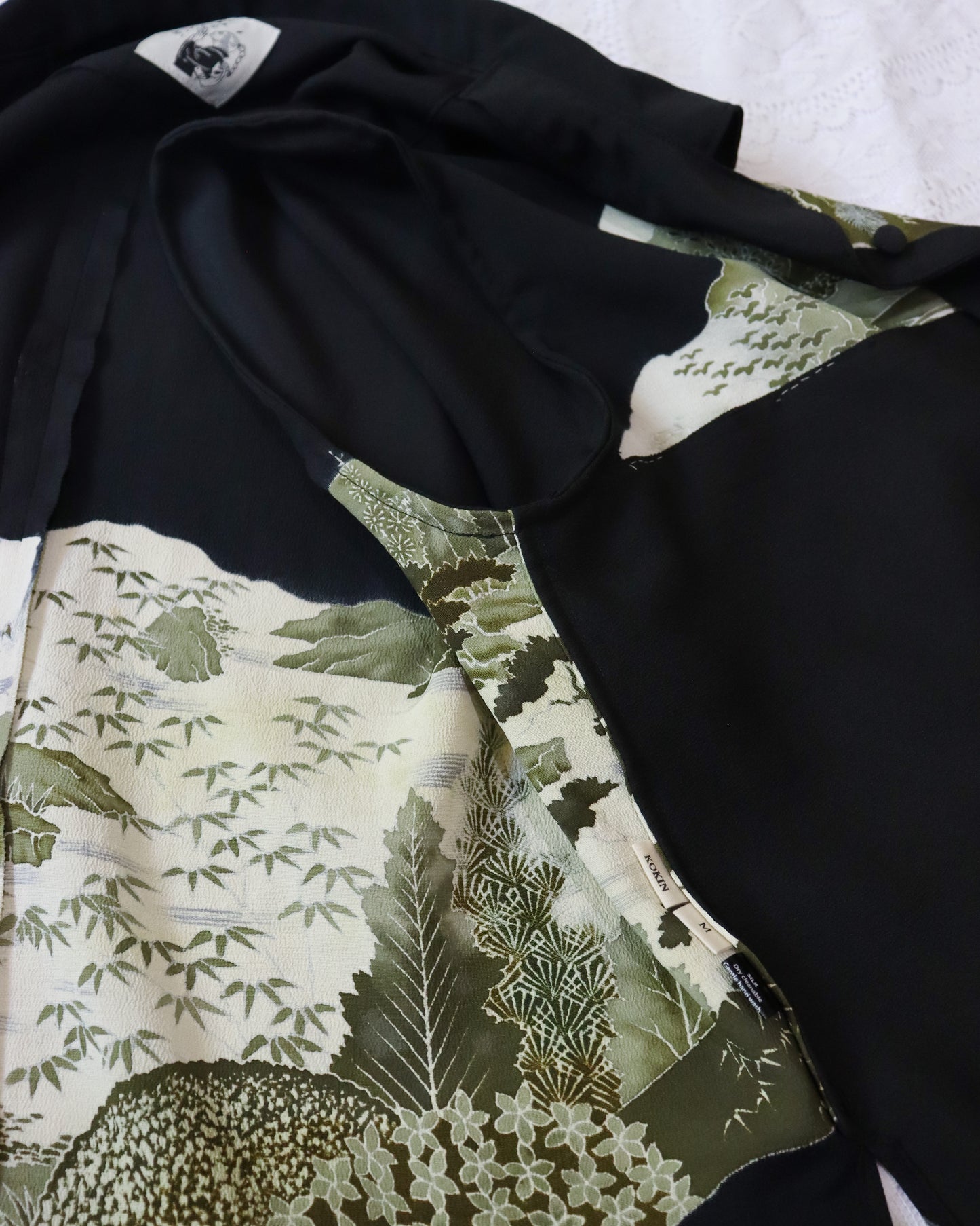Close-up of a black garment with a green leaf pattern on a white background