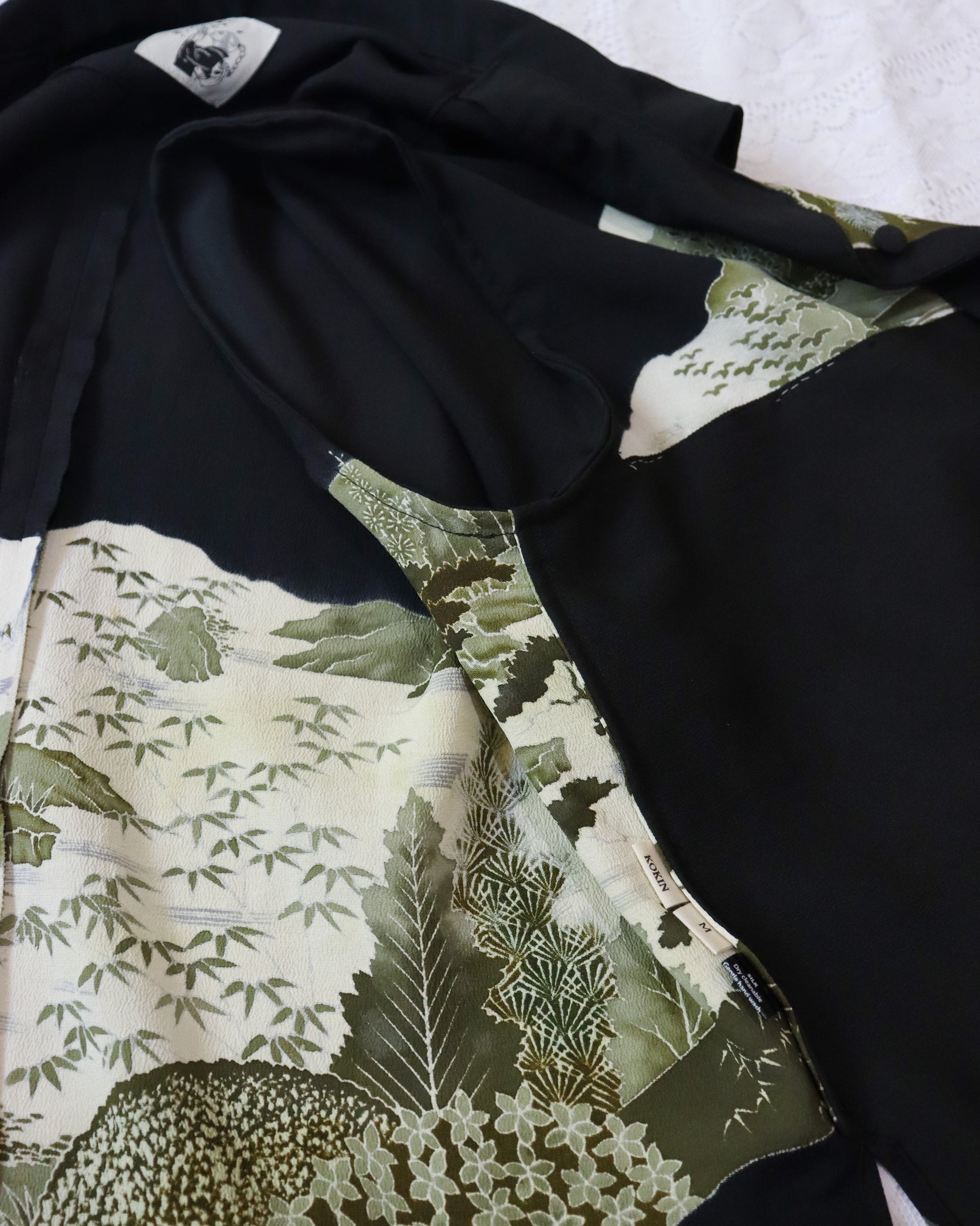 Close-up of a black garment with a green leaf pattern on a white background