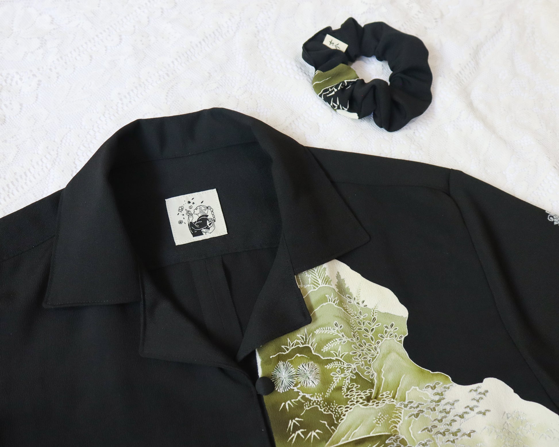 Black shirt with floral design and black scrunchie on a white background