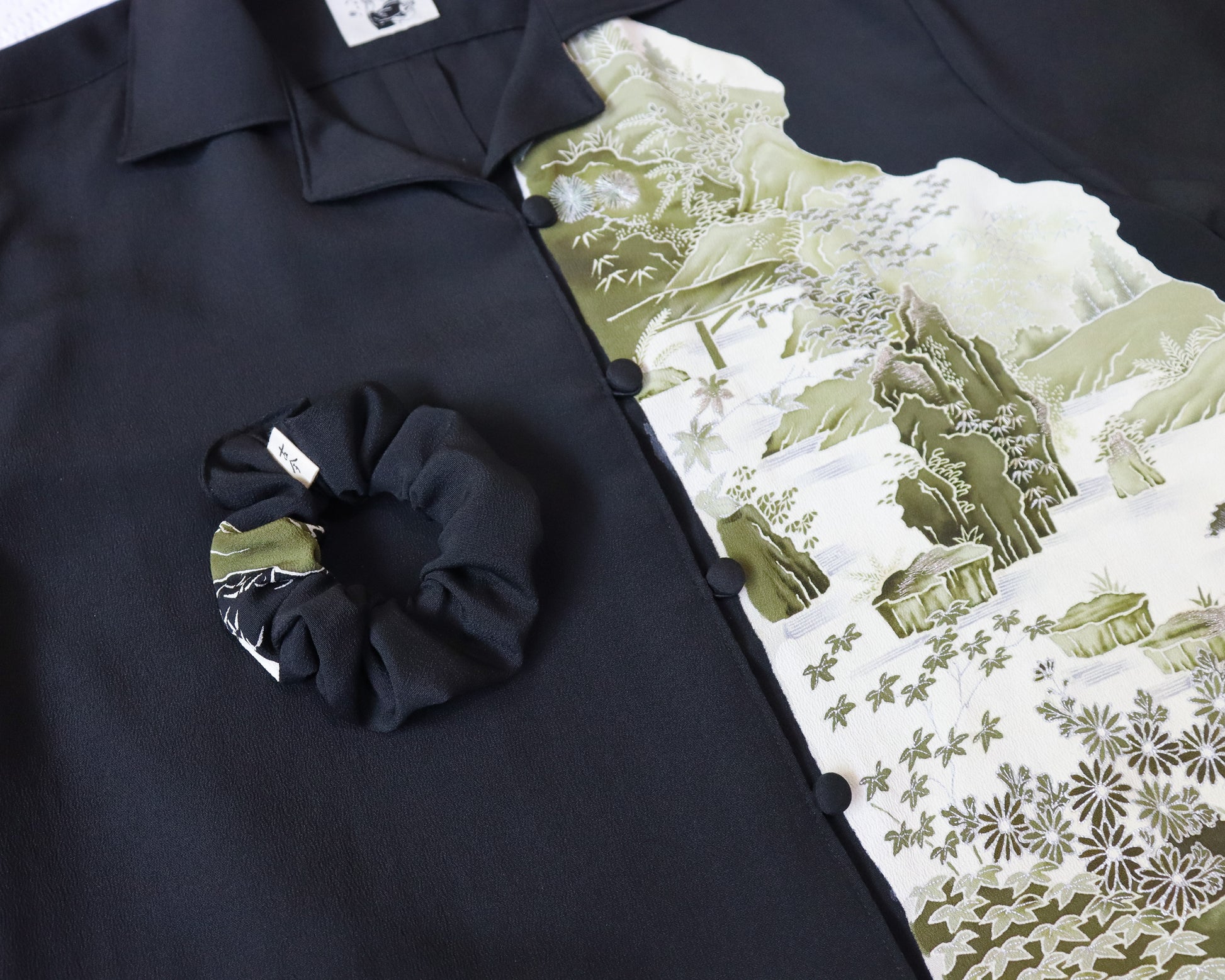 Black shirt with a scrunchie and mountain-patterned paper on a matching background