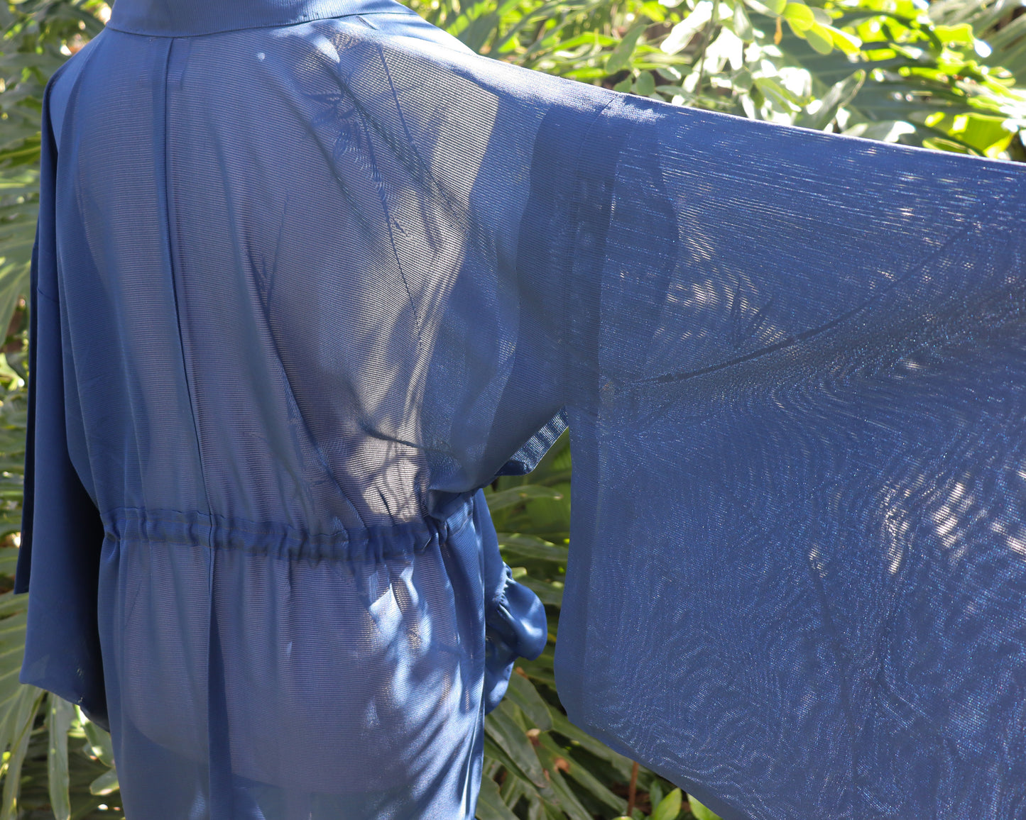 Blue garment with a textured pattern against a green leafy background